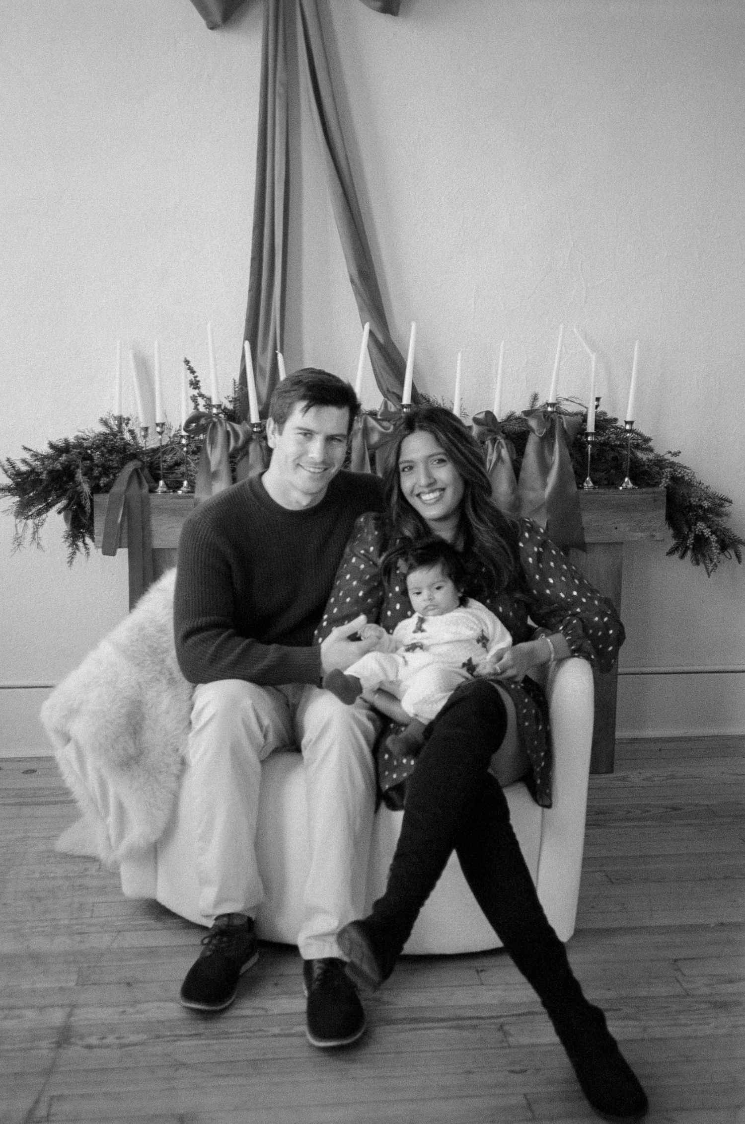 Black and white family portrait series with candid moments on a white sofa.