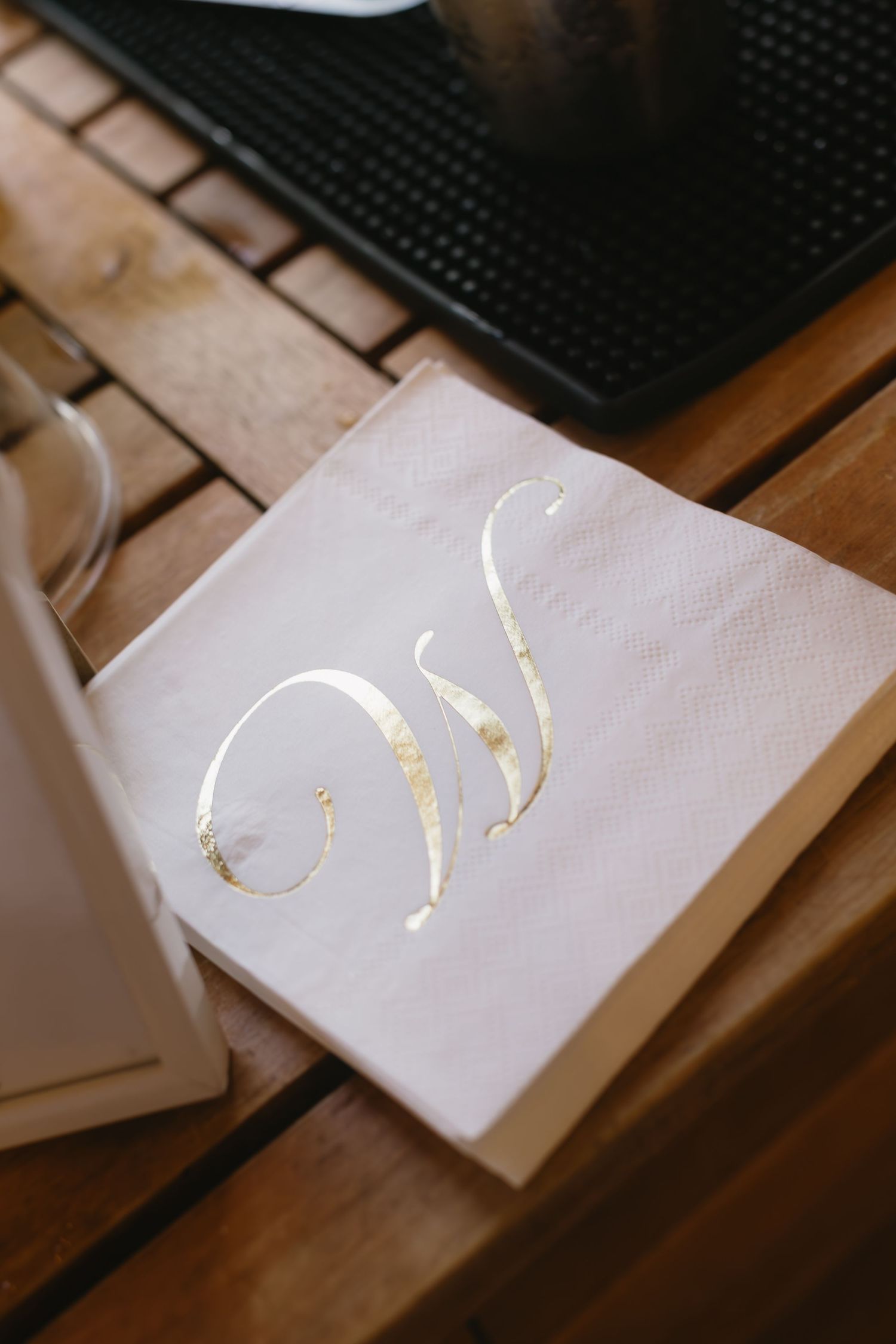 Close-up shot of white napkins with gold text details arranged on a wooden surface.