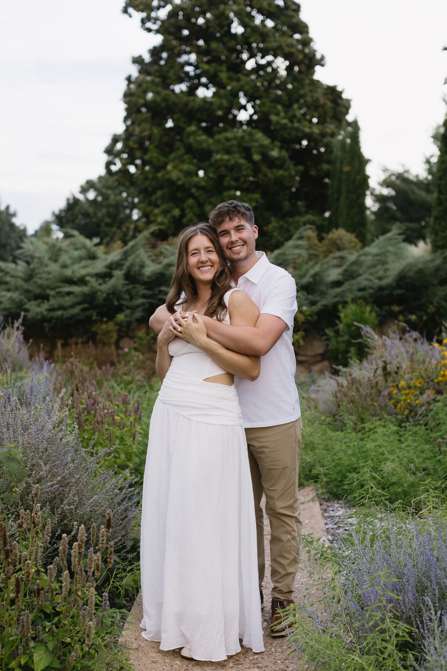 A couple embracing in a garden surrounded by blooming lavender and wildflowers.