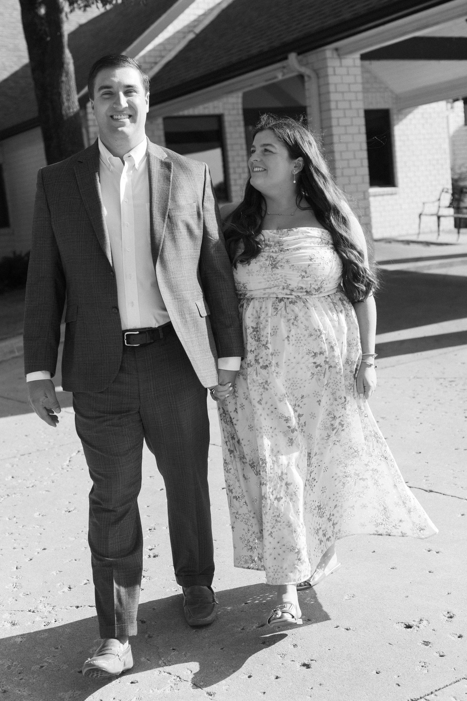 A couple in formal attire walking together, with the person in a lace dress captured from the waist down.