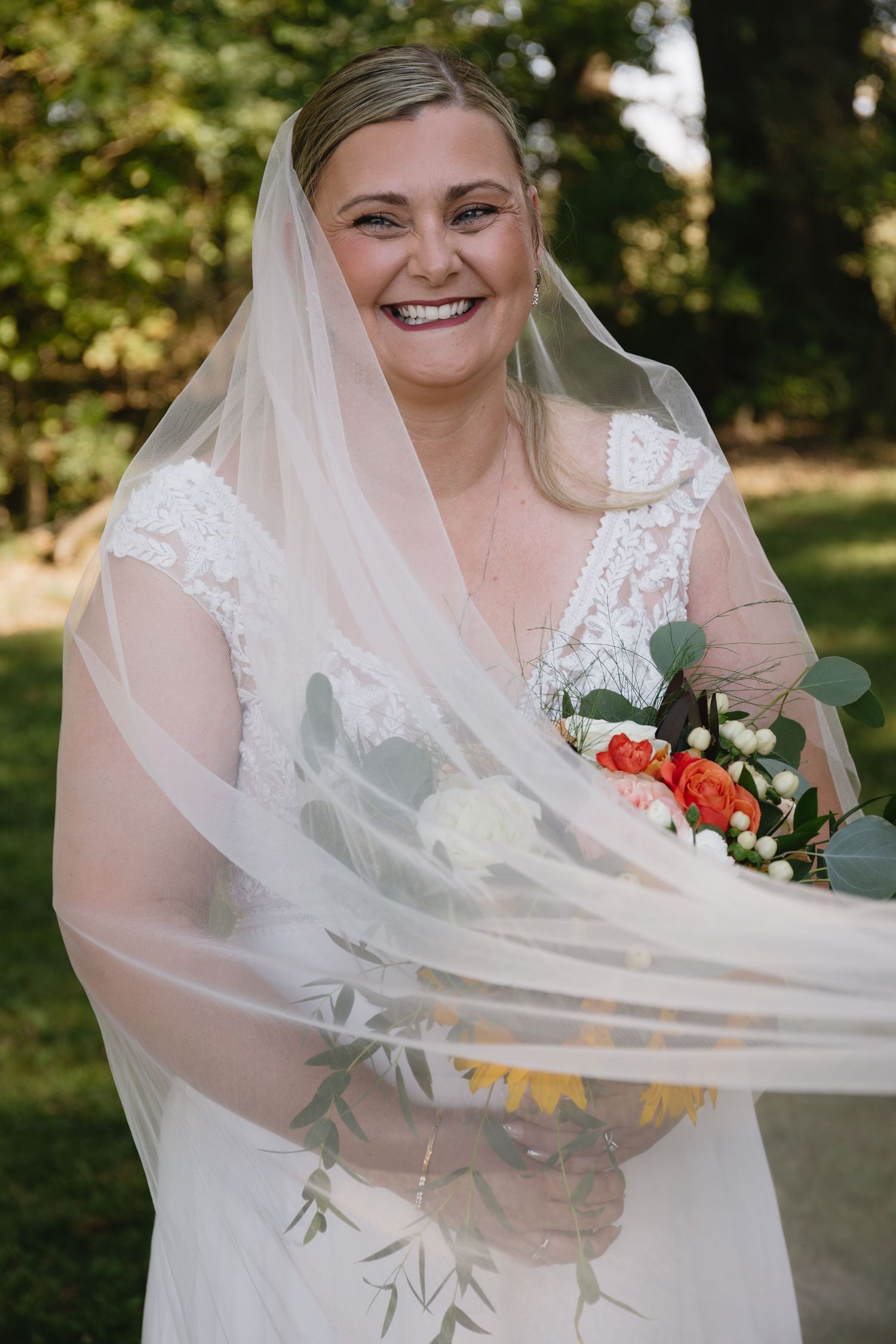 Flowing white wedding veil catching the breeze in an outdoor garden setting.