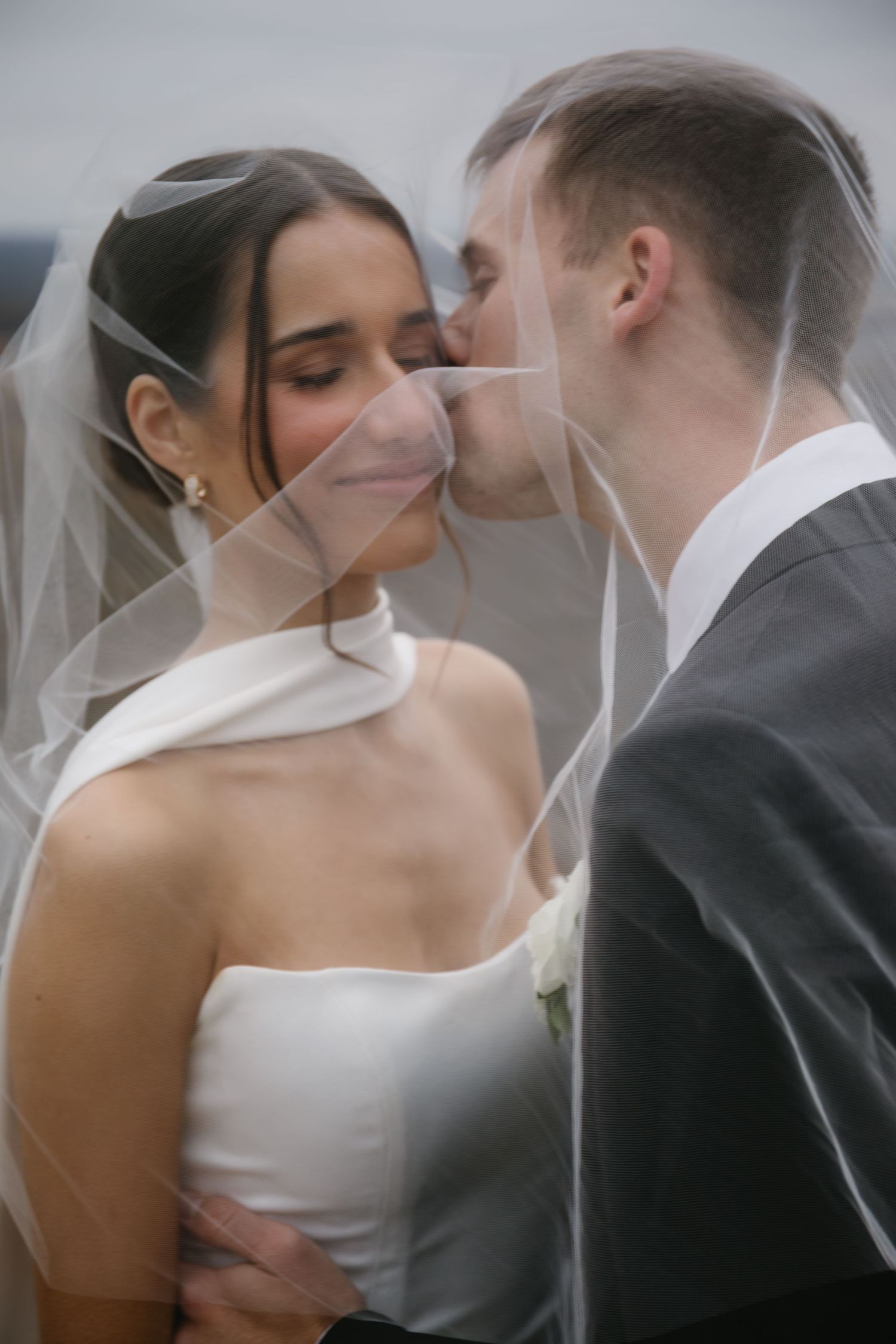 A romantic wedding moment captured through a delicate veil during an intimate ceremony.