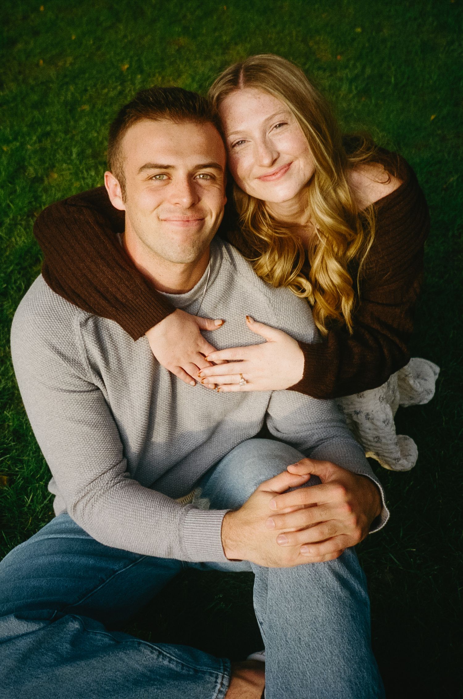 An intimate portrait of a couple cuddling together against a dark green background.