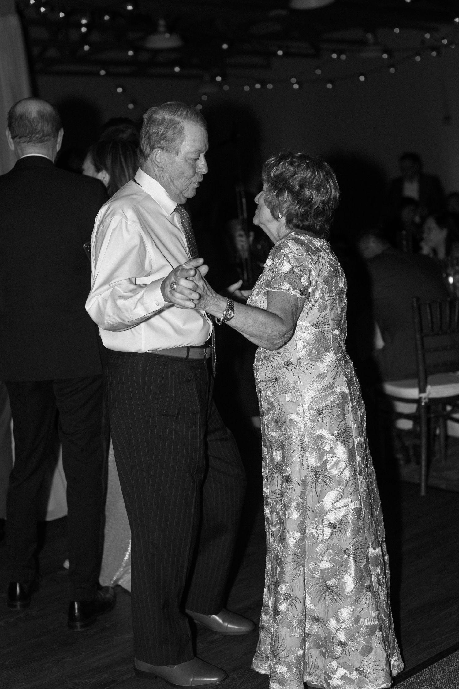 Couples slow dancing at dimly lit wedding reception.