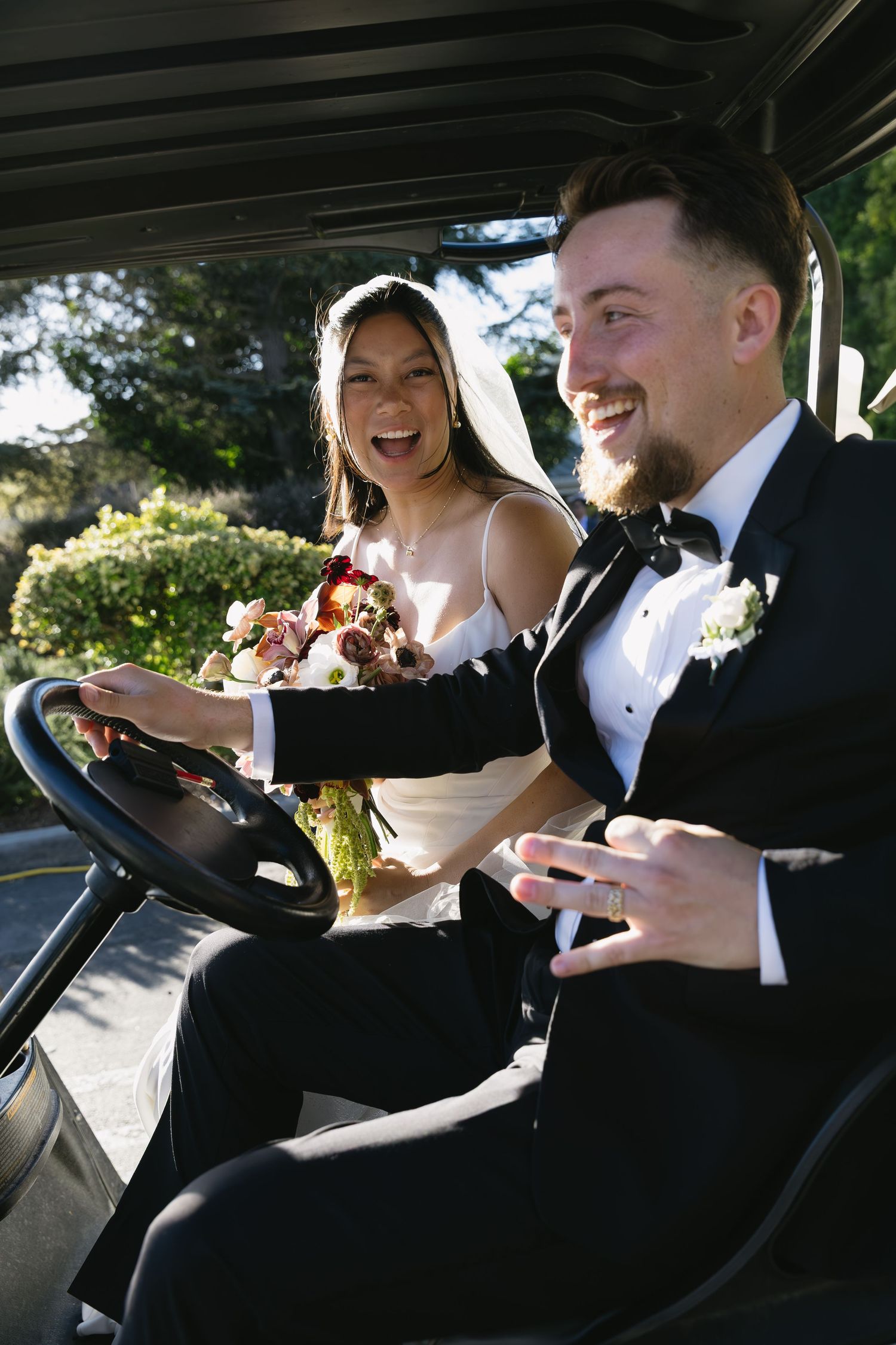 Newlyweds share a laugh while sitting in their wedding getaway car.