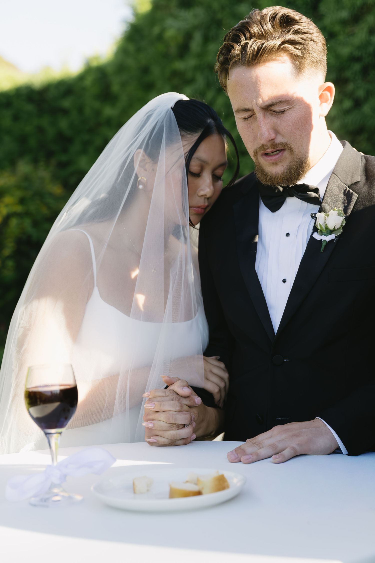 Newlyweds sharing an intimate moment at a white table during their wedding reception.
