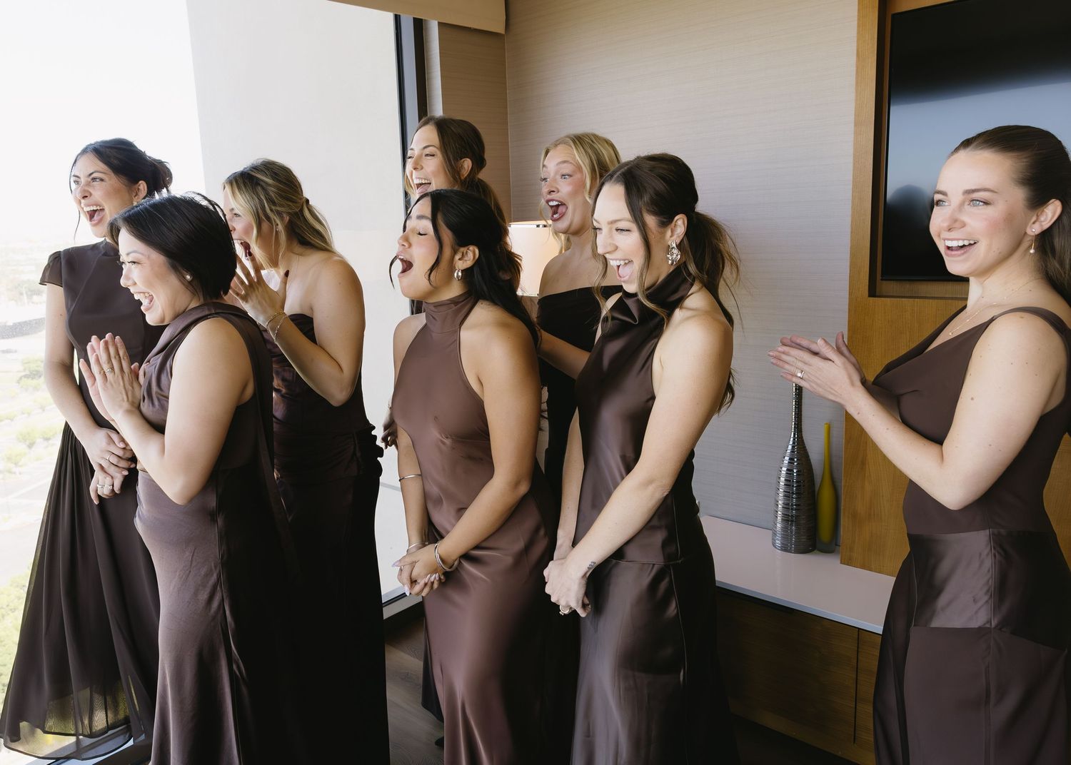 Bridesmaids in matching brown dresses standing together during a wedding ceremony.