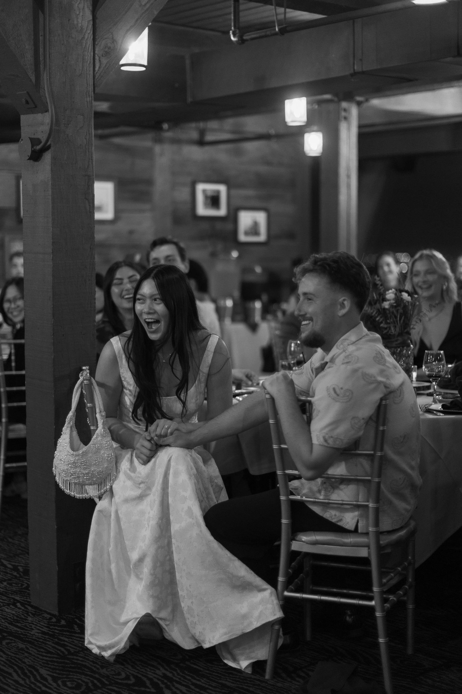 Wedding reception guests celebrate joyfully in a dimly lit indoor venue.