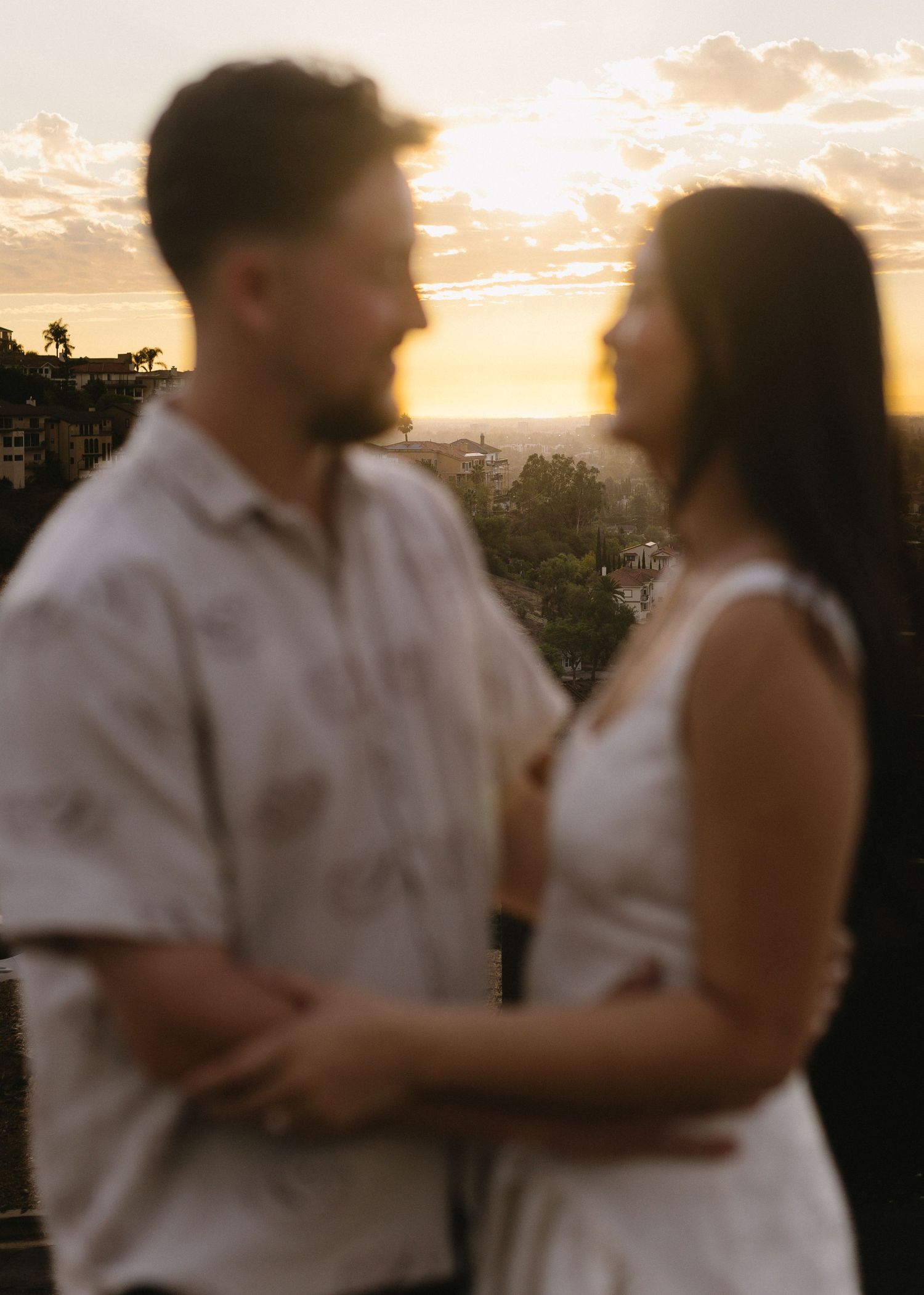 Couple poses together against a dramatic sunset backdrop during their outdoor photoshoot.