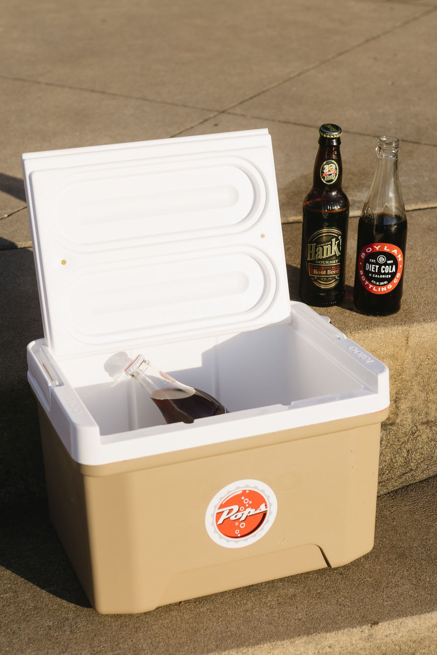 White vintage cooler with Pepsi logo and beer bottles on concrete.