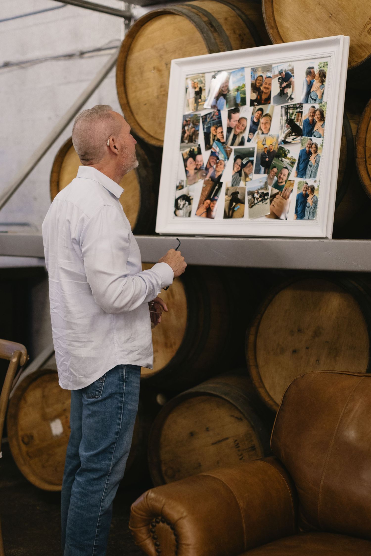 Photo gallery display against wooden wine barrels in an event venue.