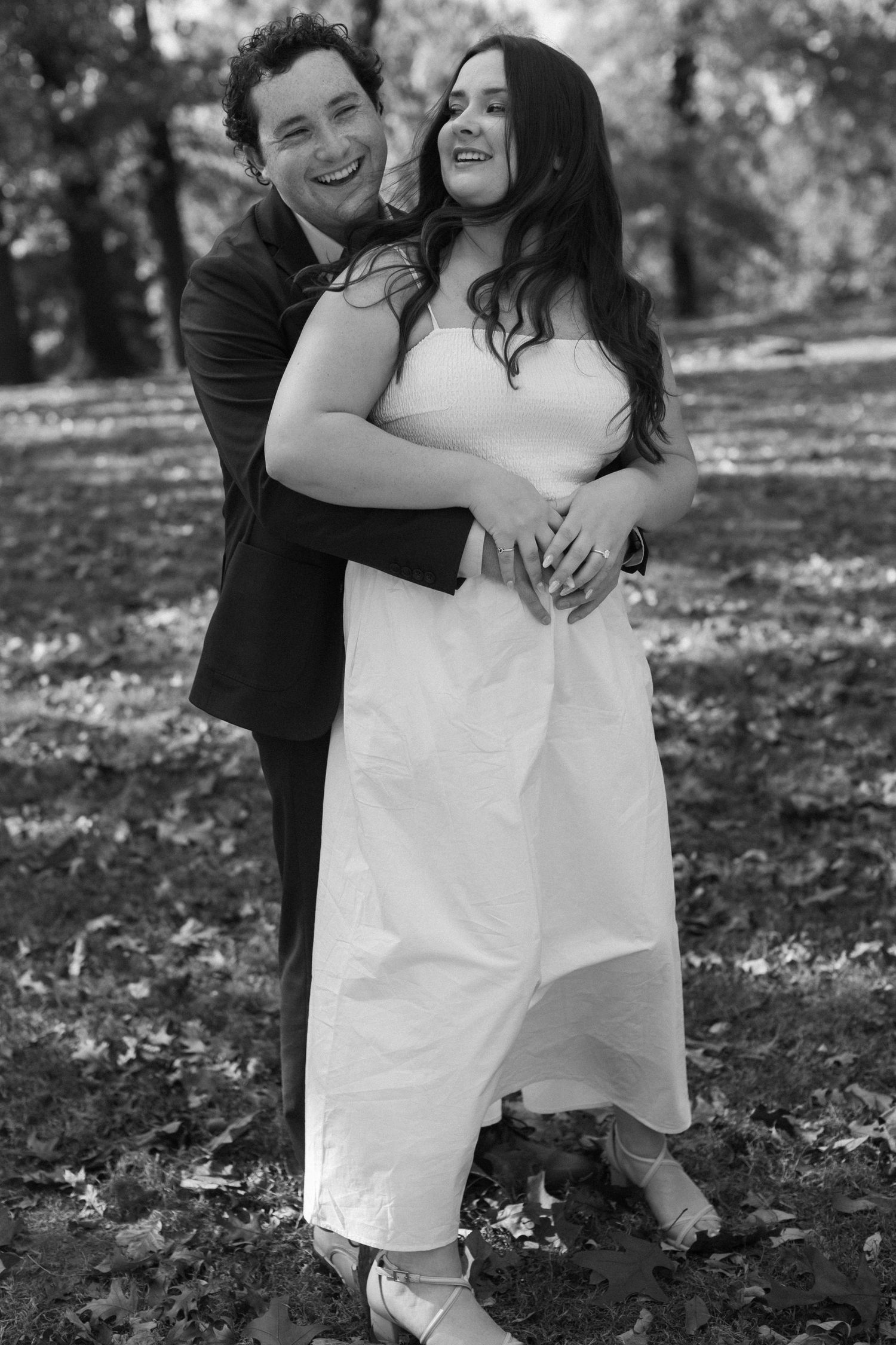 Black and white series of joyful couple embracing outdoors on fallen leaves.
