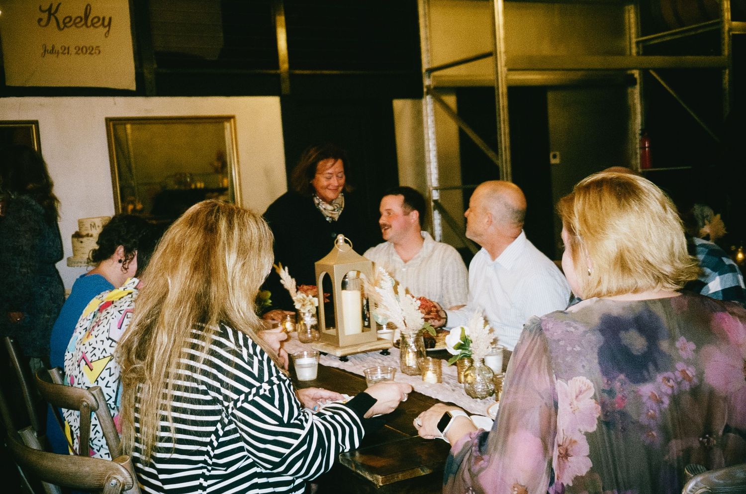 Party guests mingling and taking photos in a brick-walled venue.