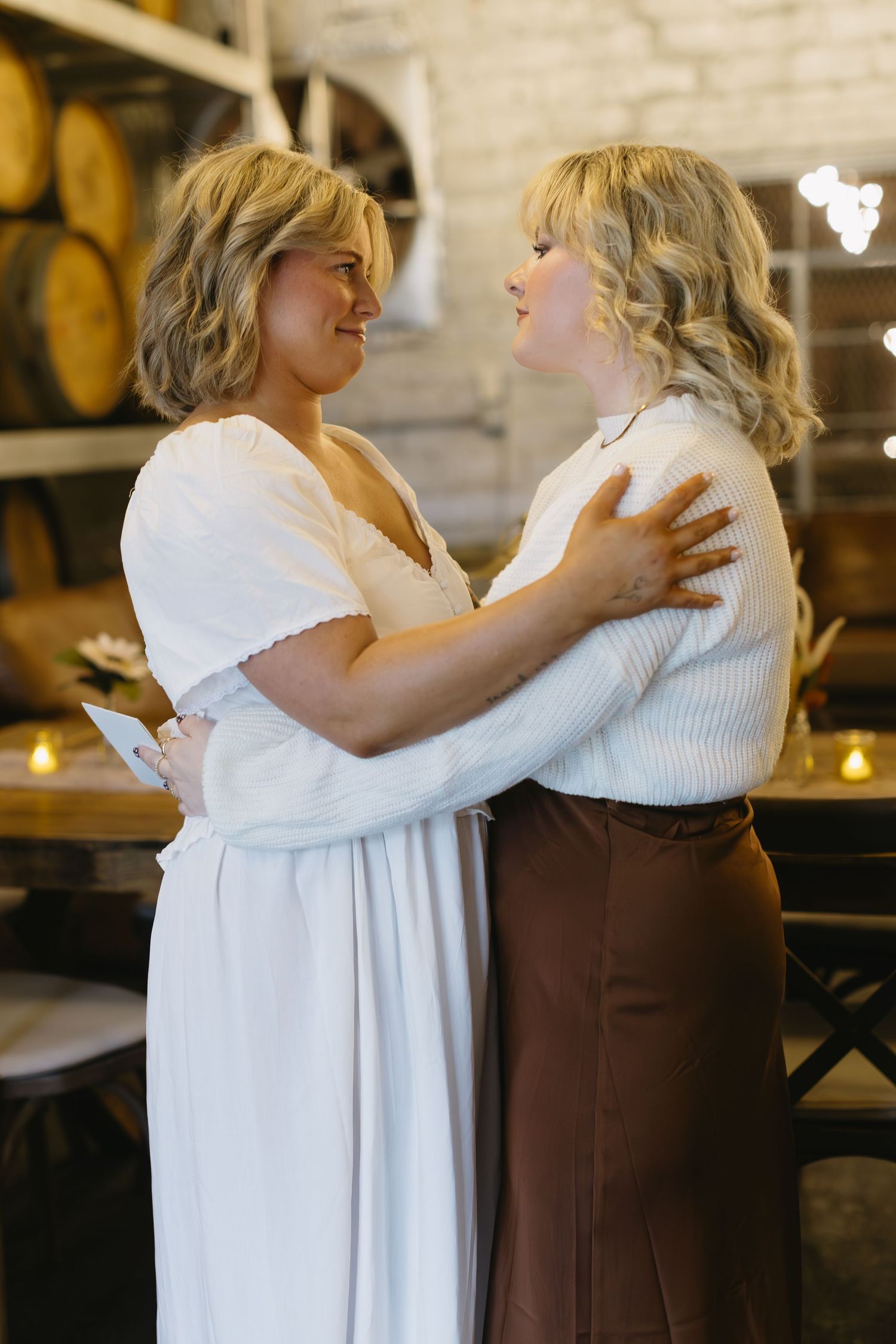Two people in white and brown outfits embrace in an intimate moment.