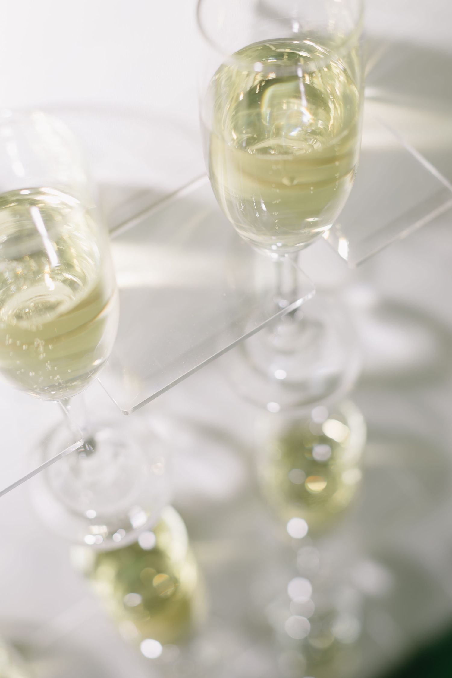 Glasses of champagne catching sunlight on white surface at wedding reception.