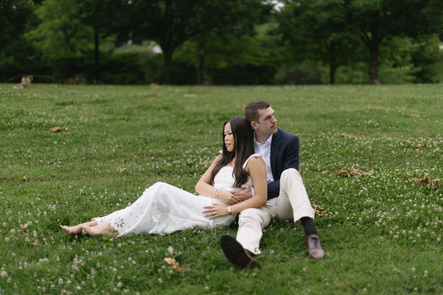 A couple sits together on grass during an outdoor wedding photo session.