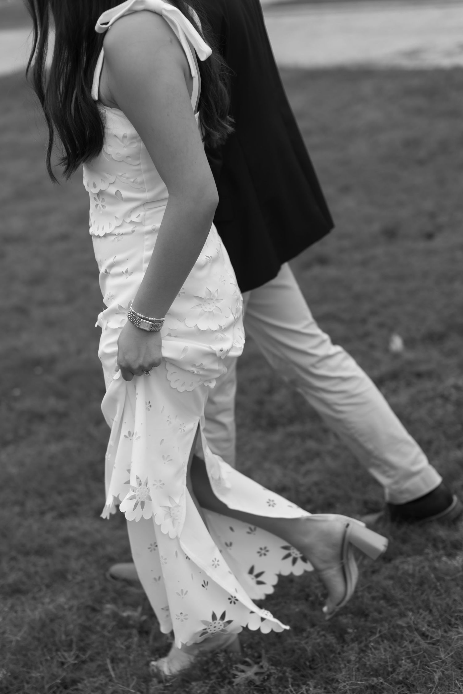 Black and white detail shot of feet and dress hem during an outdoor wedding photoshoot.