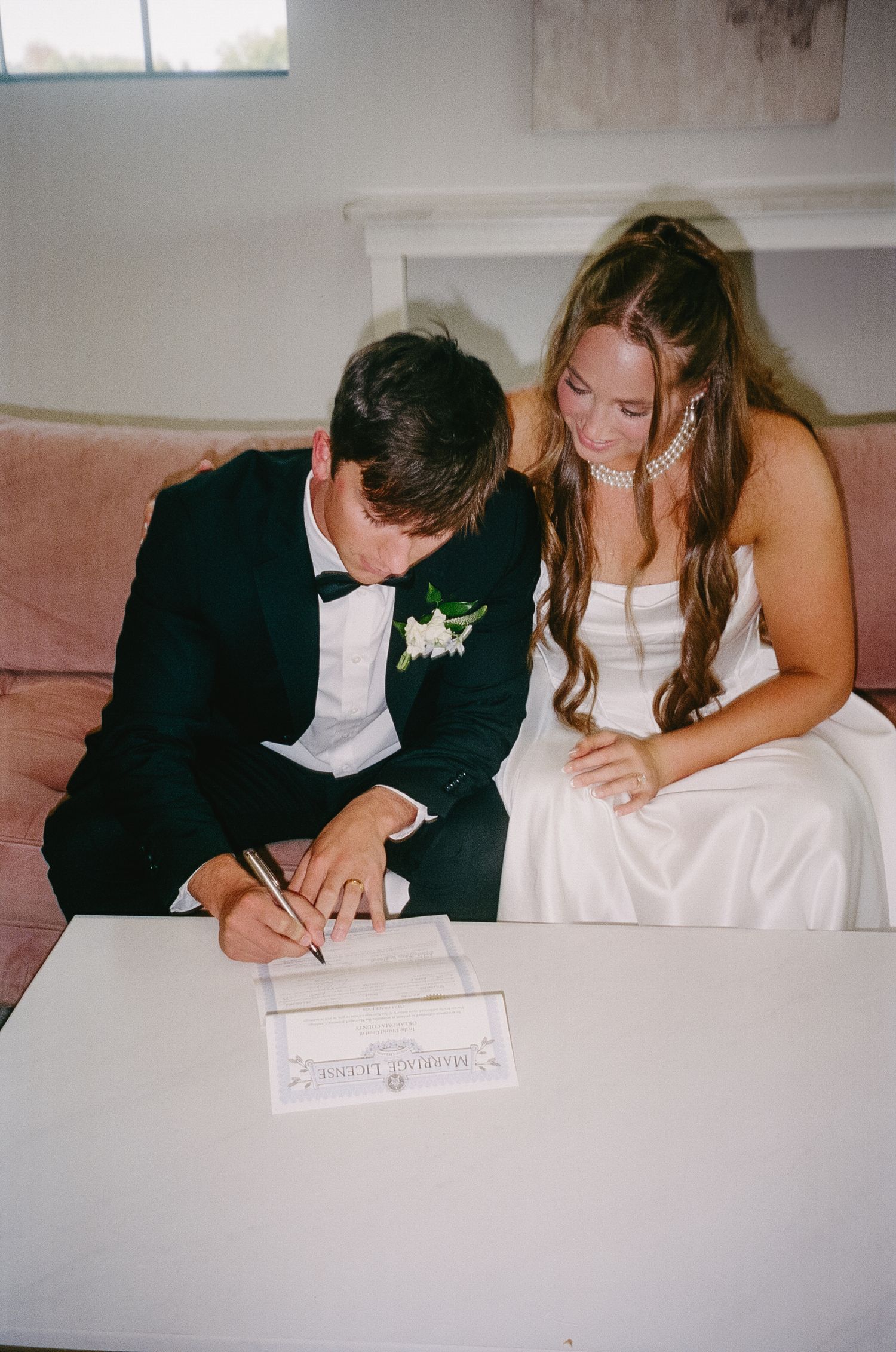 Couple signing marriage paperwork and documents together during their wedding ceremony.