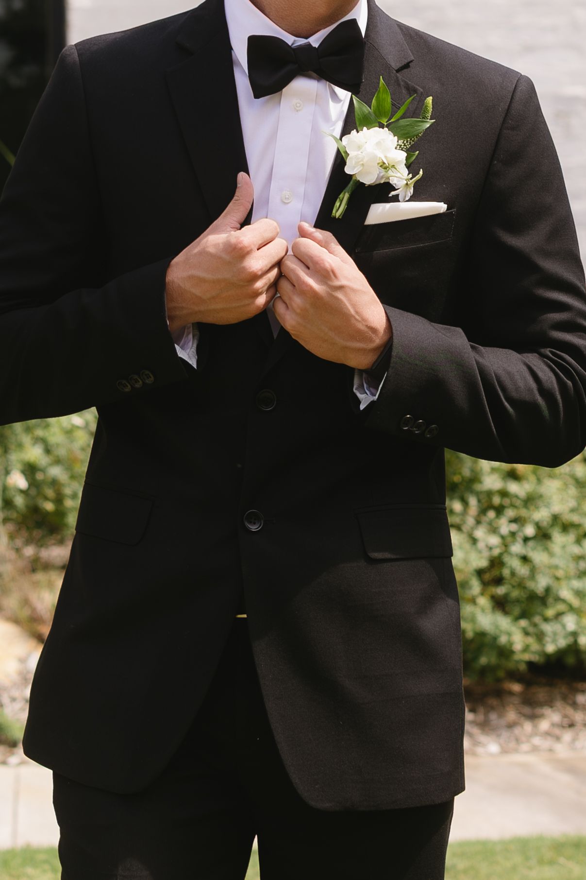 Close-up of formal black tuxedo with white boutonniere and pocket square.