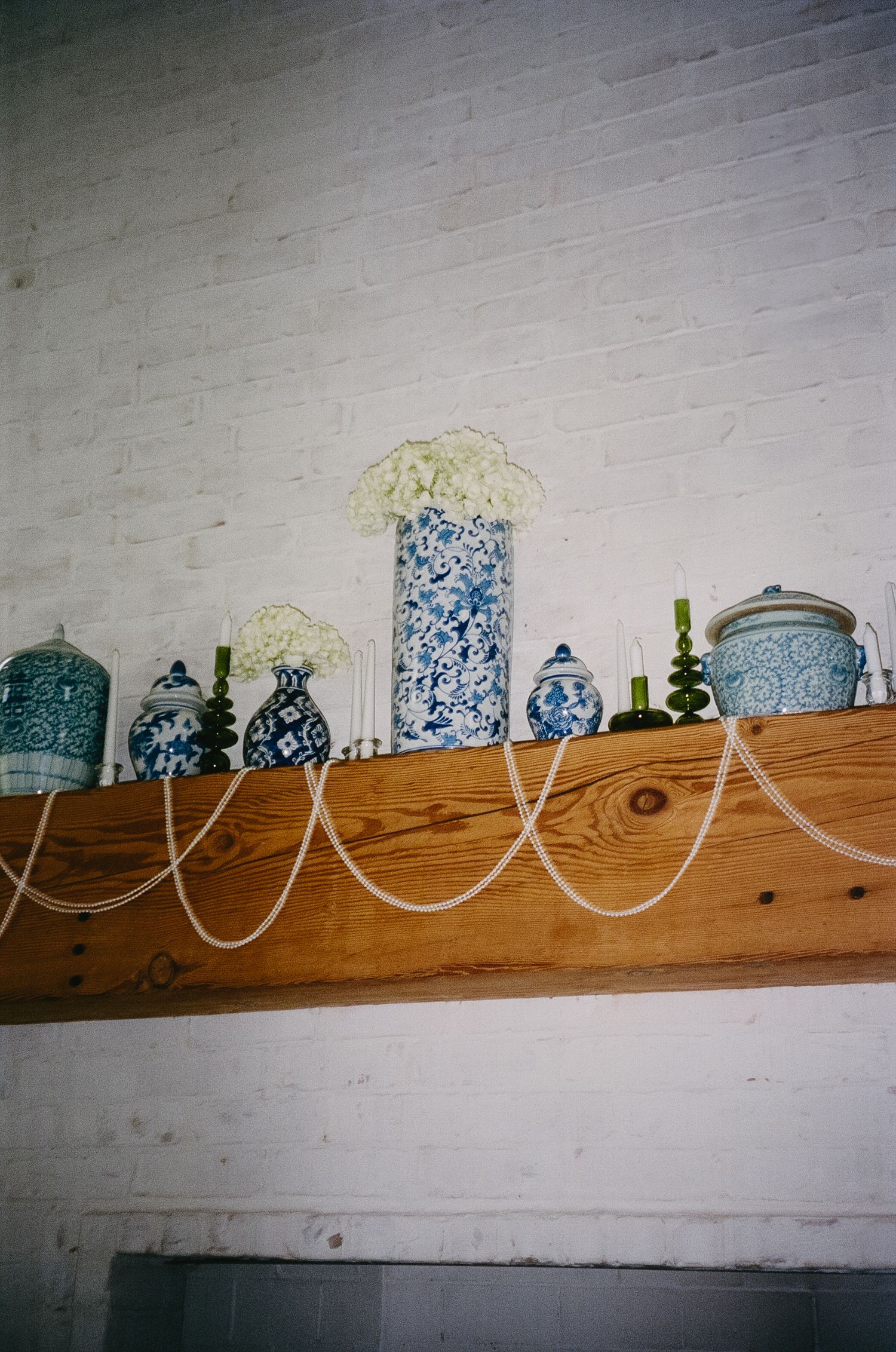 Decorative blue and white porcelain vases and bottles displayed on a rustic wooden beam shelf against a white wall.