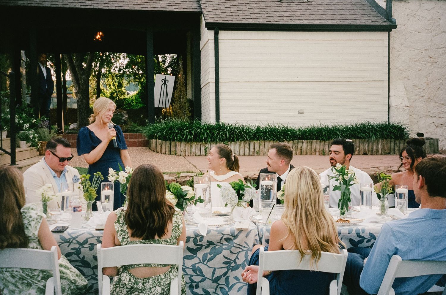 Wedding reception guests seated at decorated outdoor tables with blue and white linens.