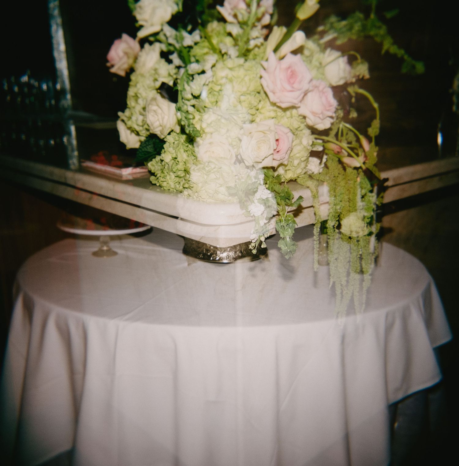 White and pink floral centerpieces on tables with white linens.