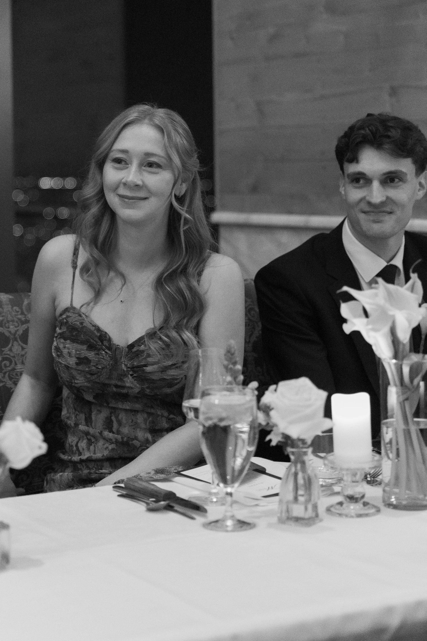 Wedding reception guests enjoying dinner at an elegantly set table with formal place settings.