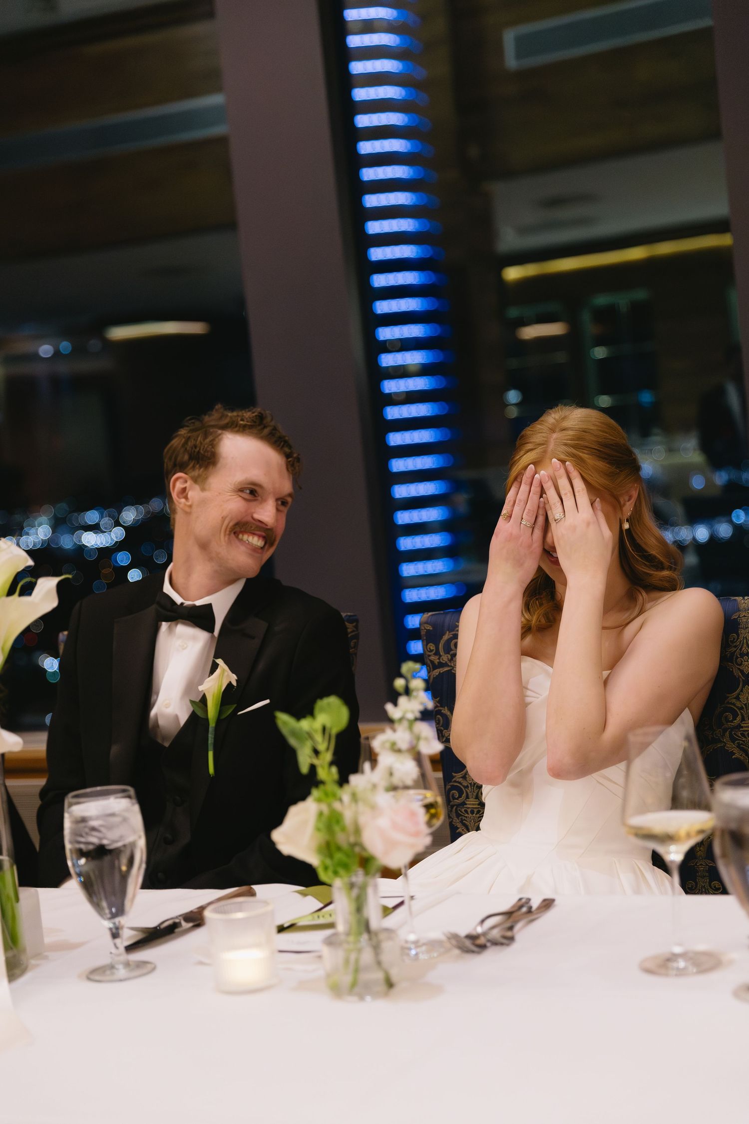 Wedding reception guests share laughs at an elegantly decorated dining table.