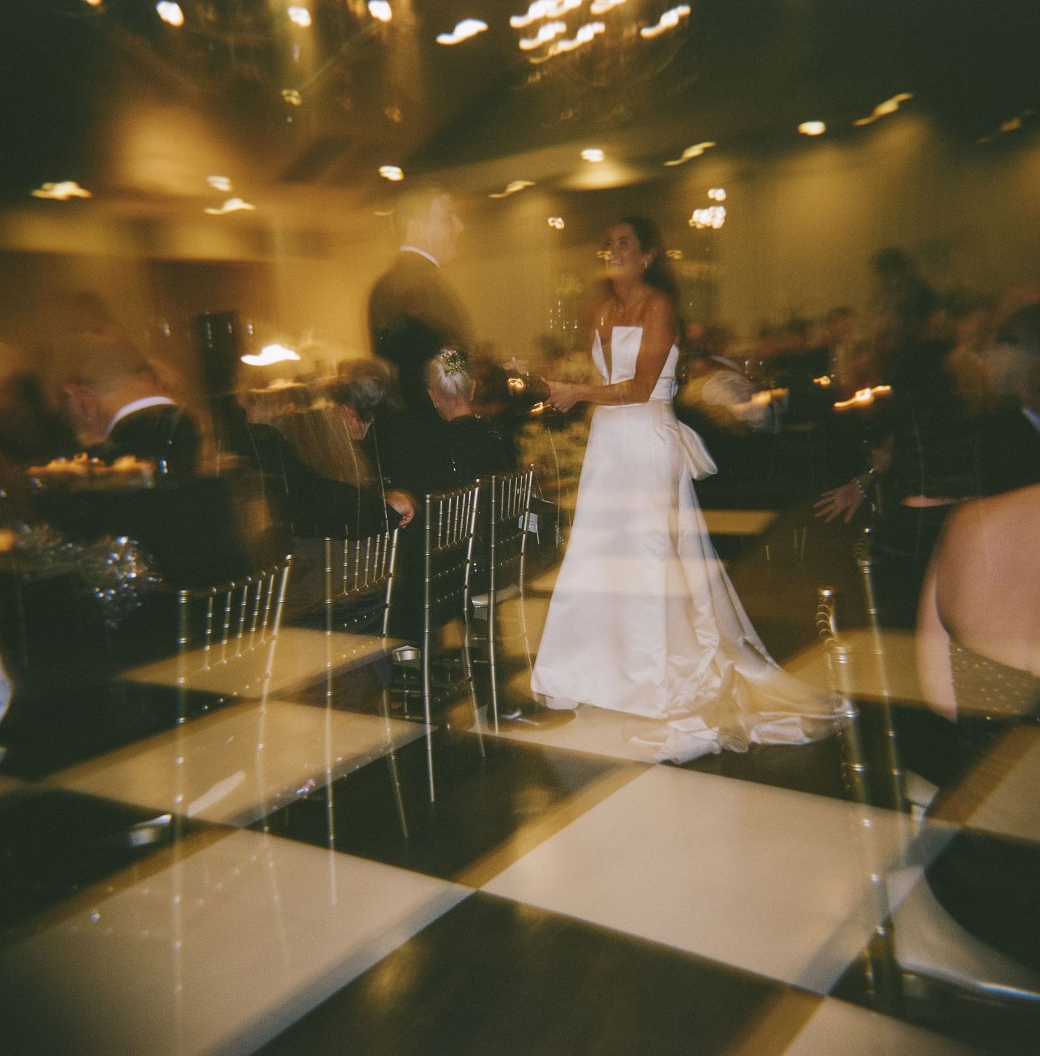 Wedding reception scene on a black and white checkered dance floor with motion blur effects.
