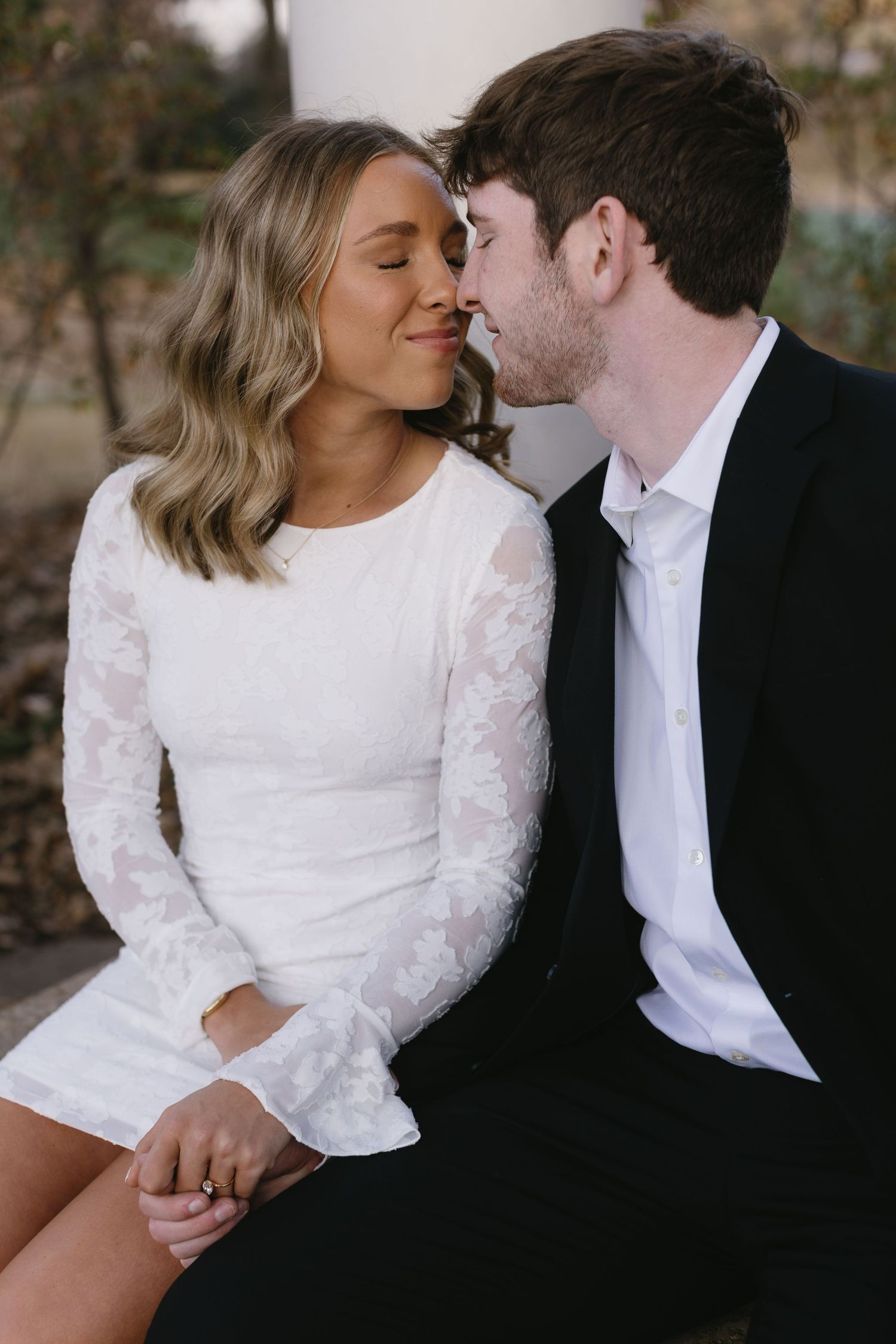 An intimate close-up of a couple sharing a tender moment, with the bride in white lace and groom in black.