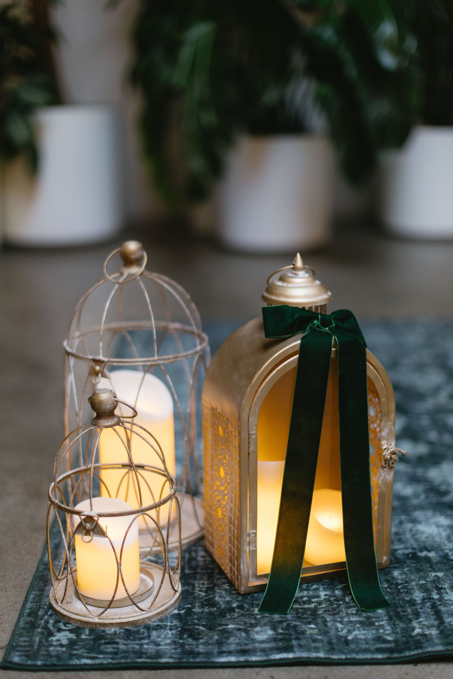 Glowing glass lanterns with black ribbons arranged in a row on a textured surface create warm ambient lighting.