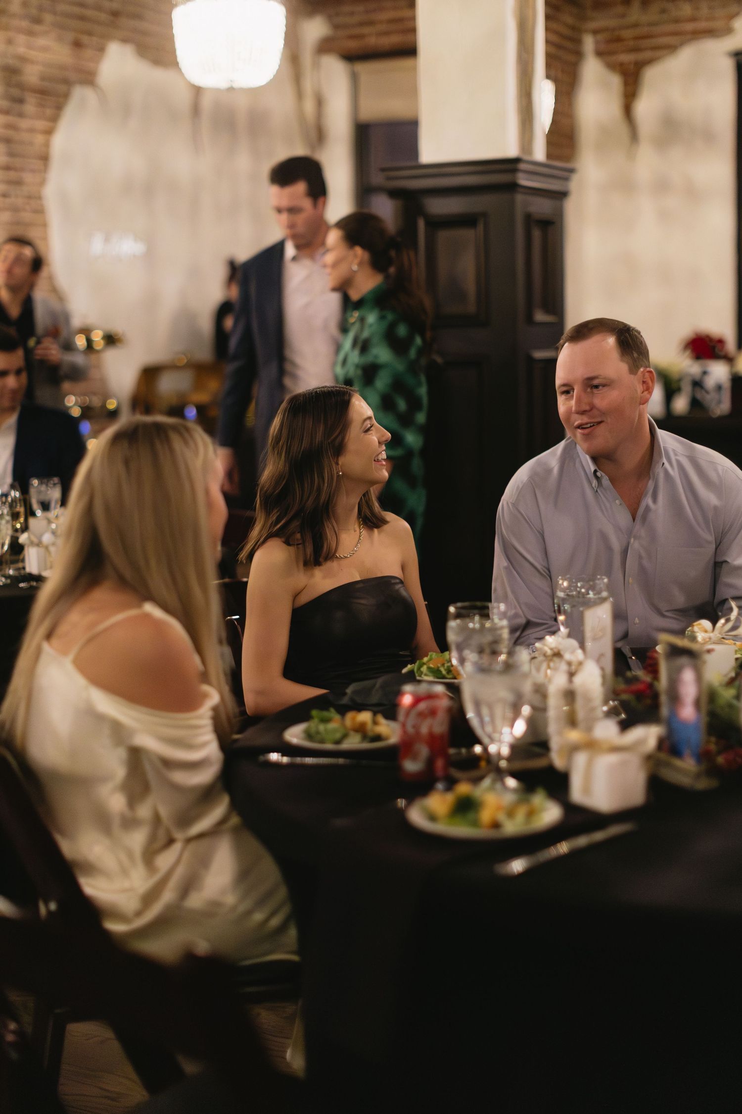 Guests enjoying dinner and conversation at an elegant restaurant with ambient lighting.