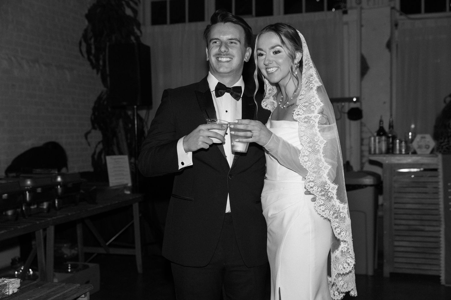 Wedding couple shares a celebratory toast at their reception in black and white.