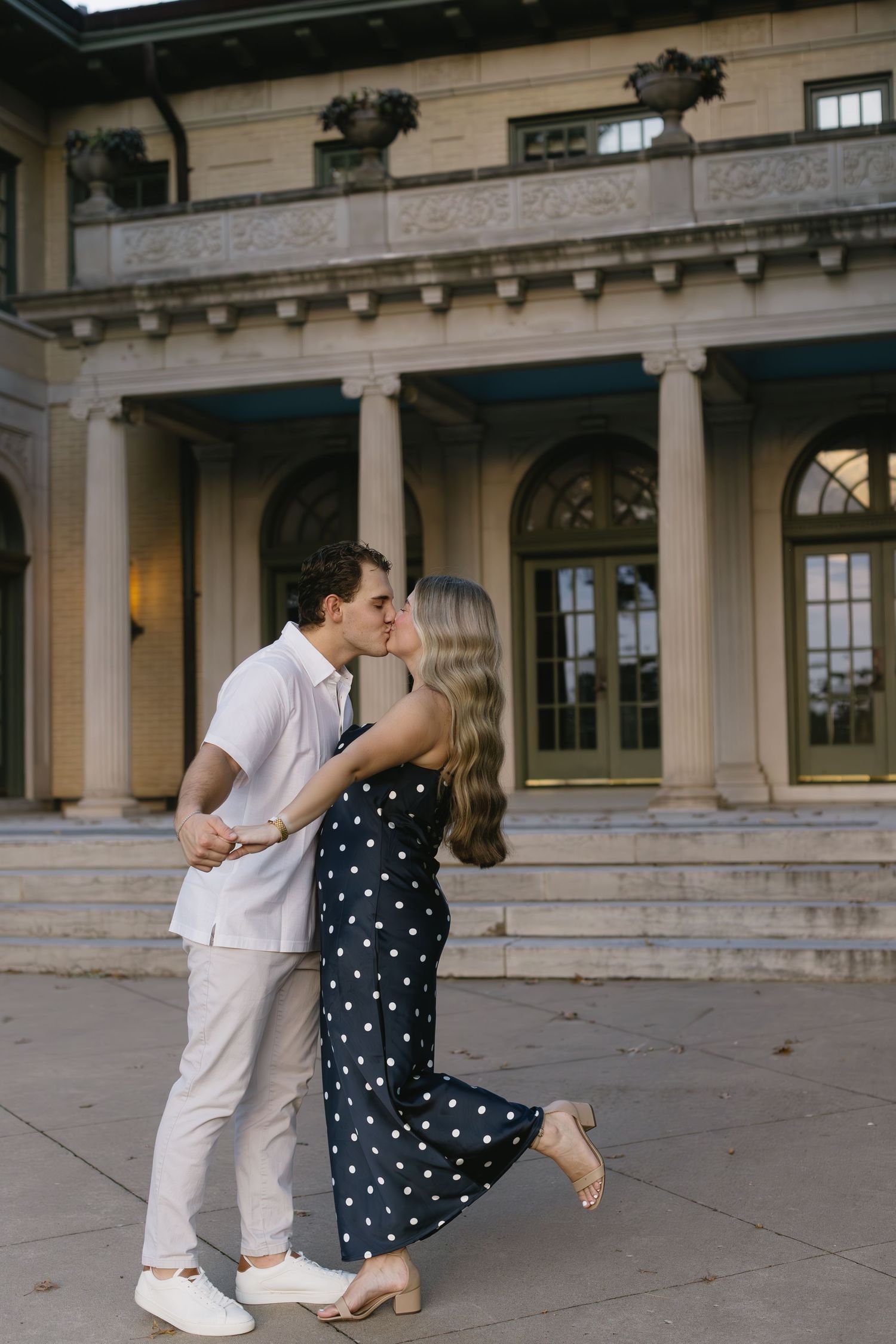 A romantic dance sequence unfolds on a columned terrace with a polka dot dress and white outfit creating elegant contrast.