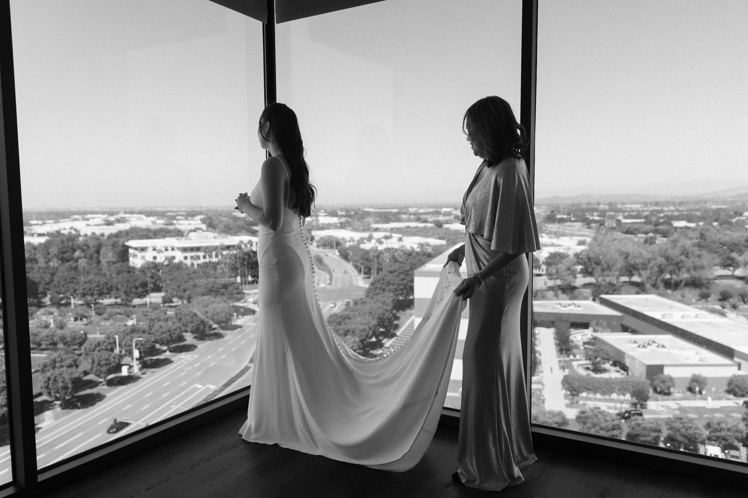 A figure stands in silhouette against large windows overlooking an urban landscape.