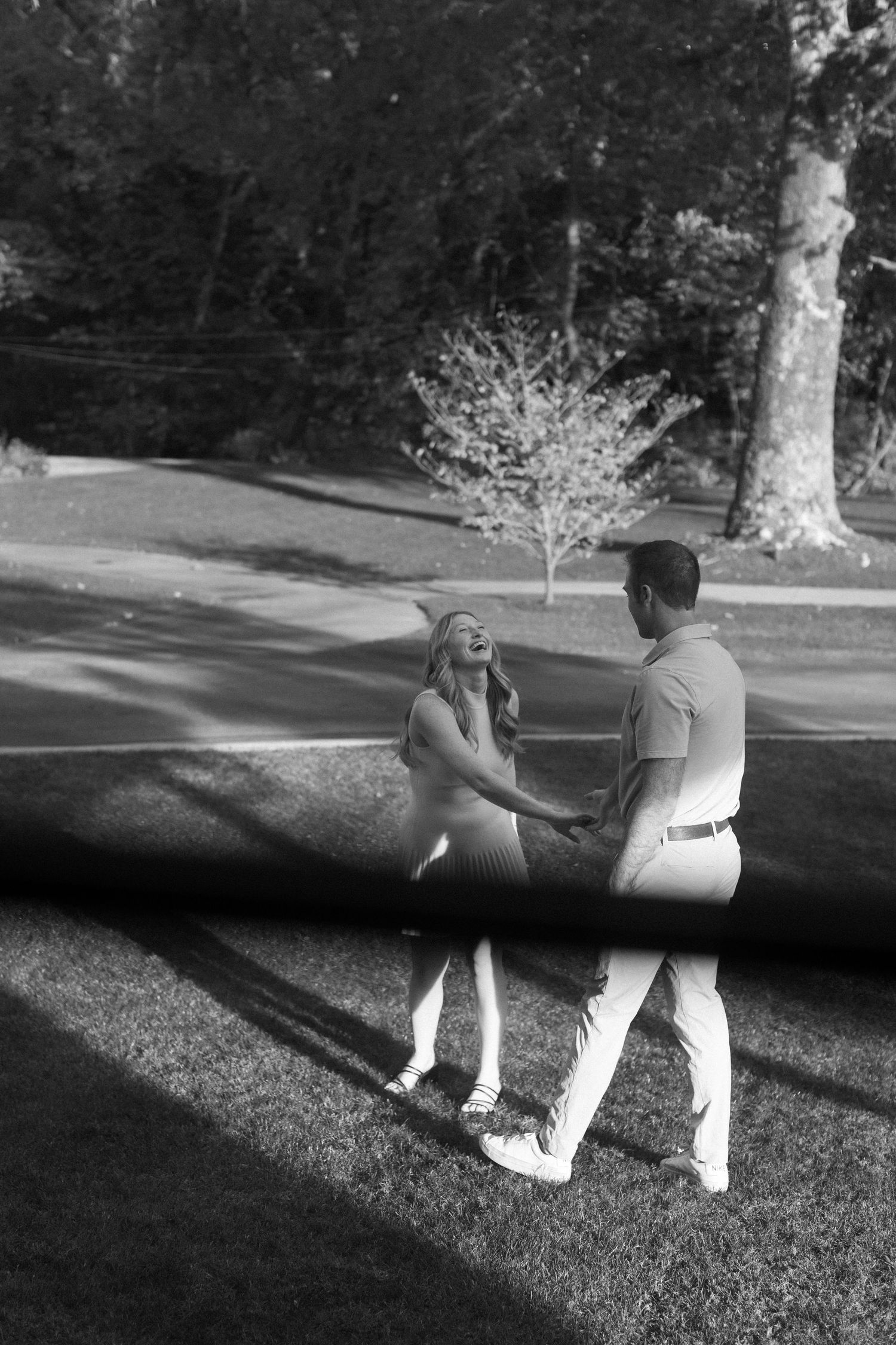 Two people sit together on grass in a park during golden hour.