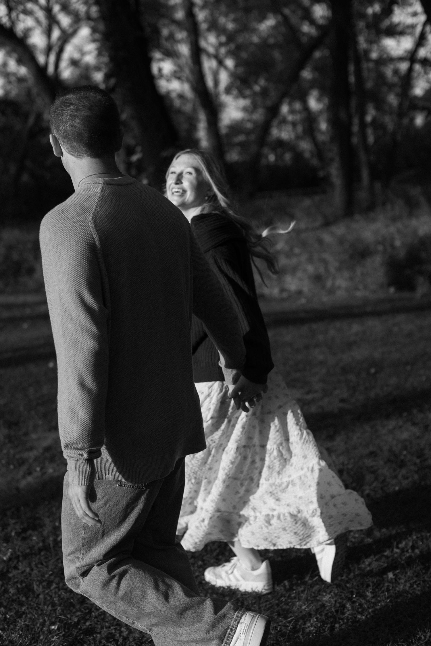 Black and white artistic photos of couple walking together in wooded setting.