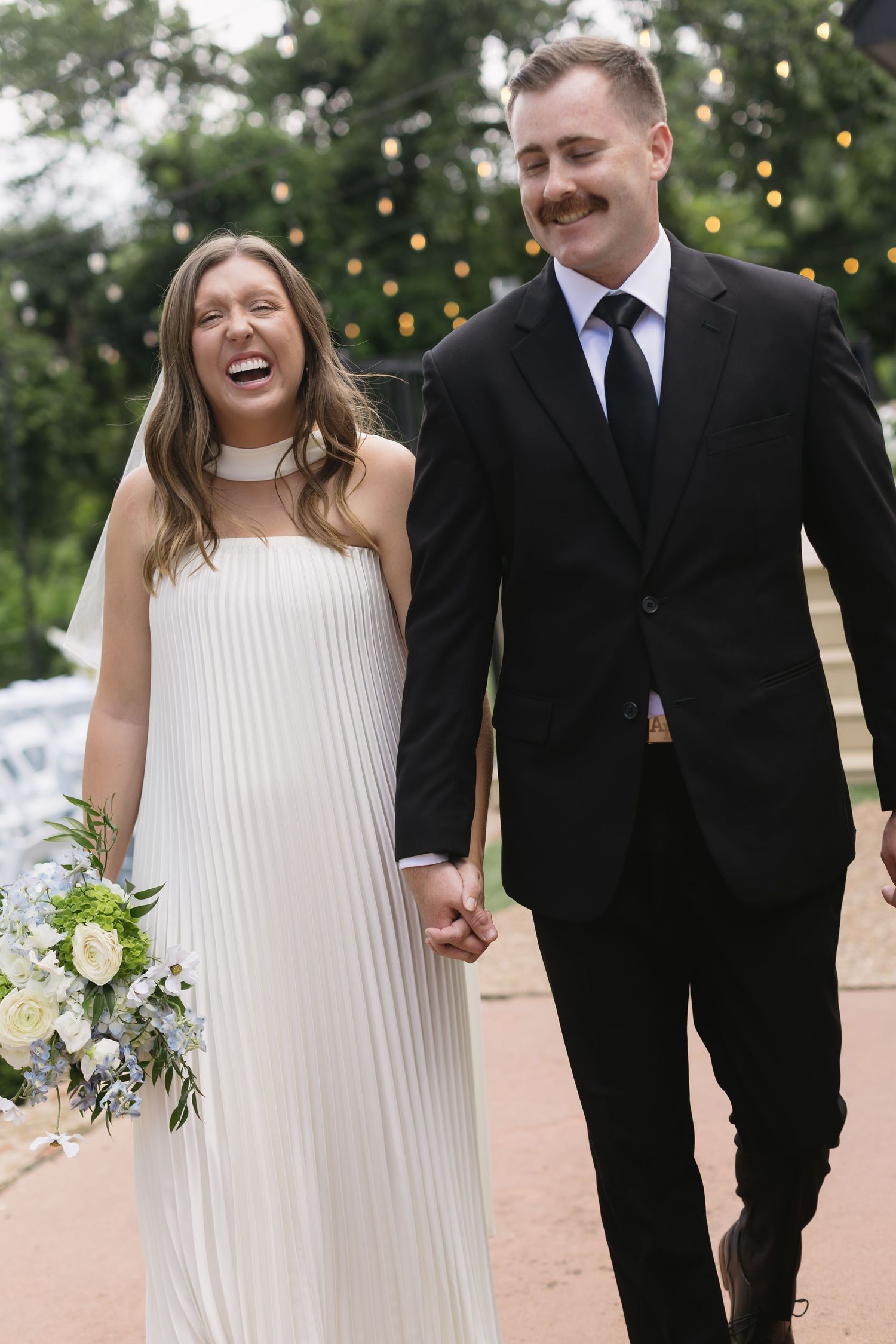 Couple in wedding attire share a joyful moment outdoors.