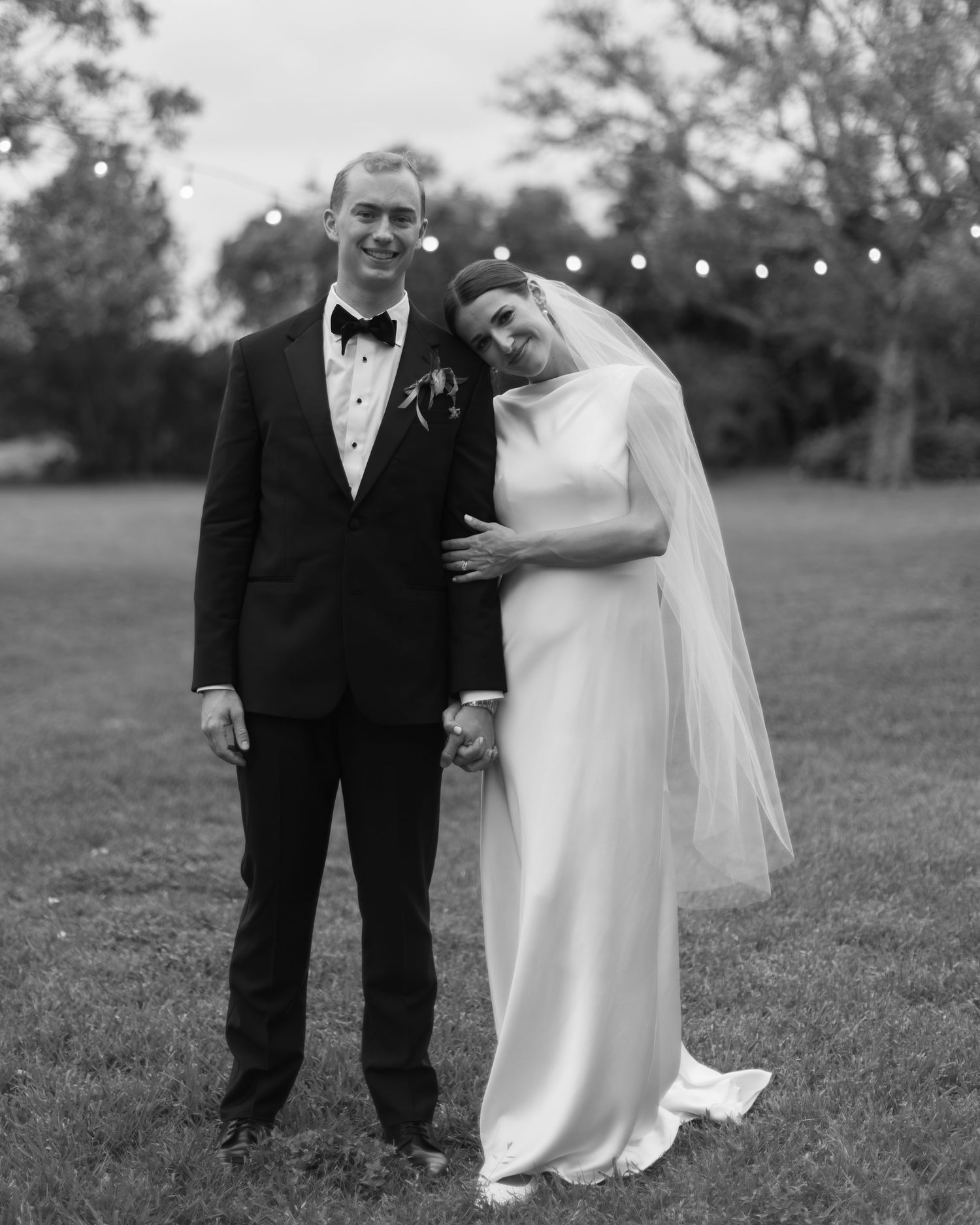 Black and white wedding portraits of a couple posing together on a grassy field.
