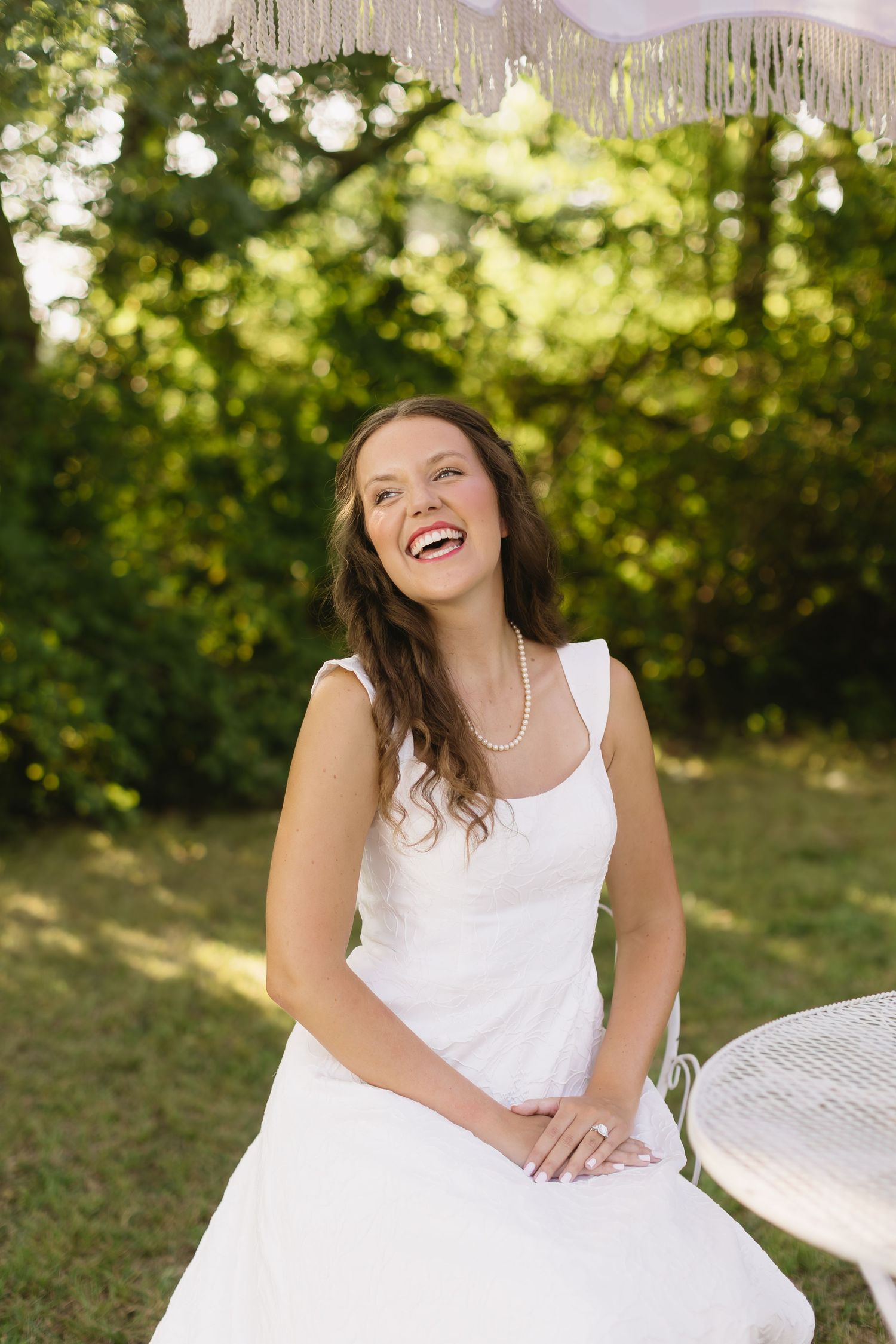 A bright outdoor bridal portrait with bokeh lighting effects and a white dress.