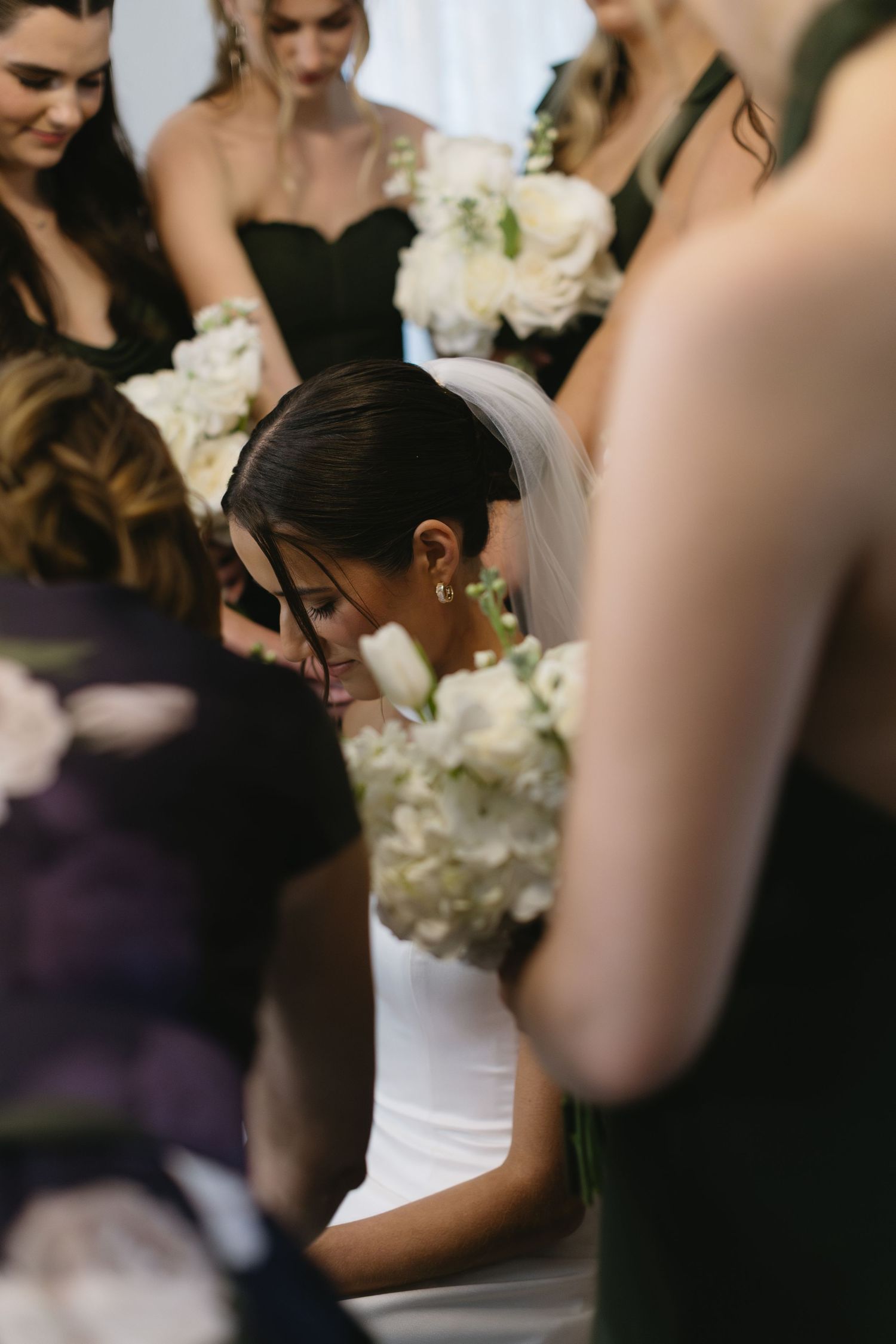 Wedding party members in black dresses holding elegant white floral bouquets.