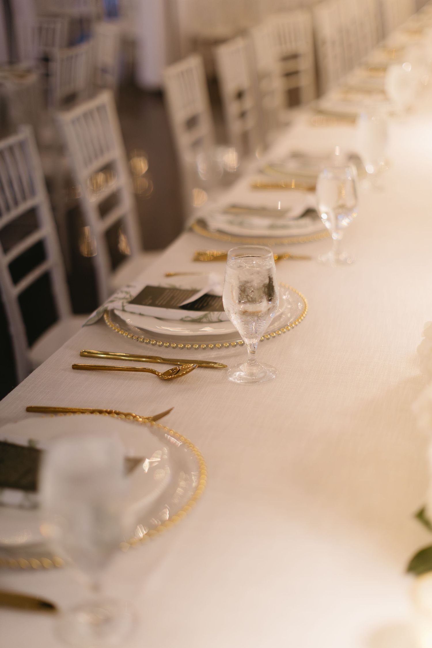 Elegant table settings with gold accents and white linens at a formal reception.