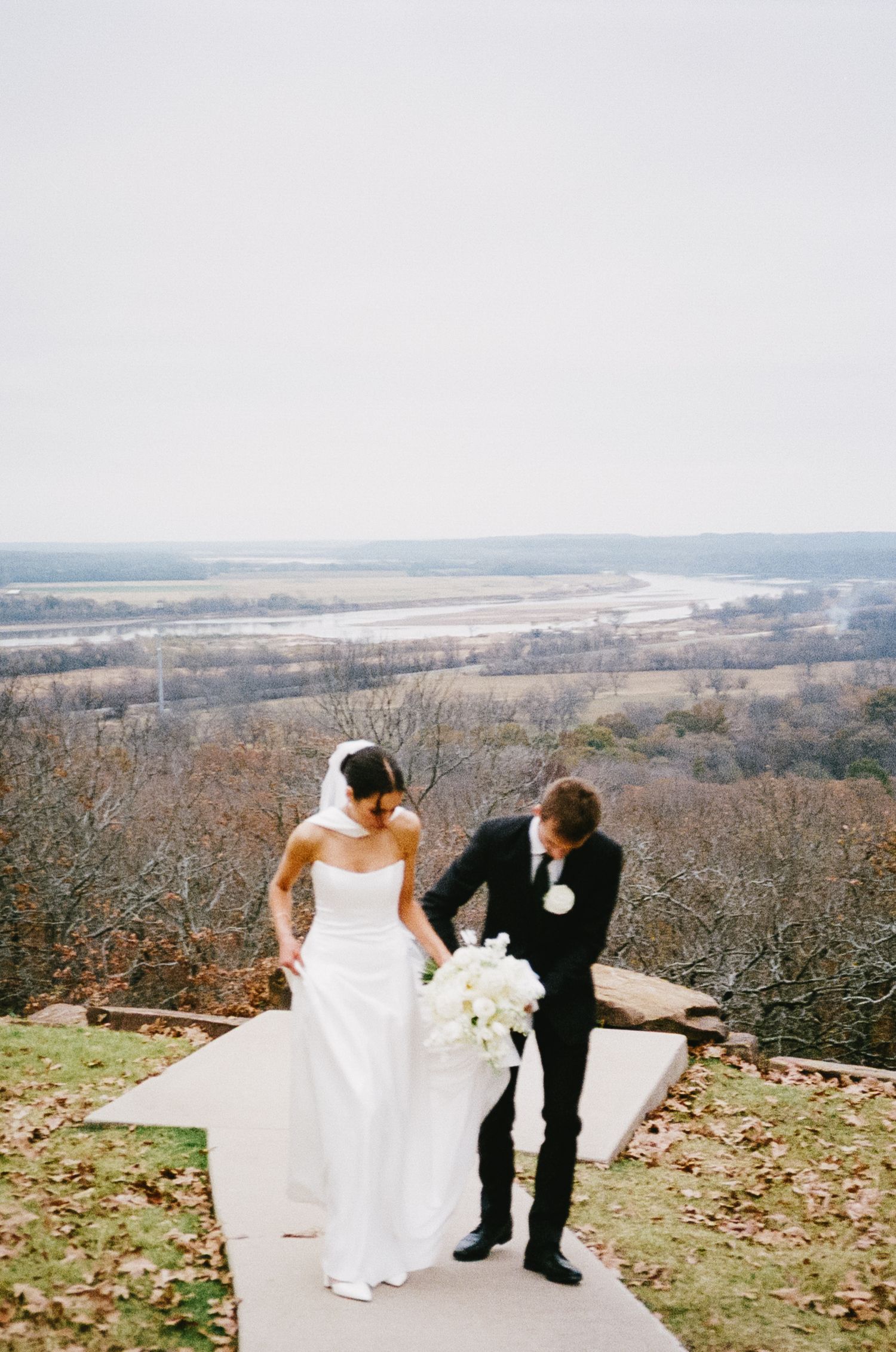 Scenic wedding photos overlooking a vast autumn landscape with fallen leaves.