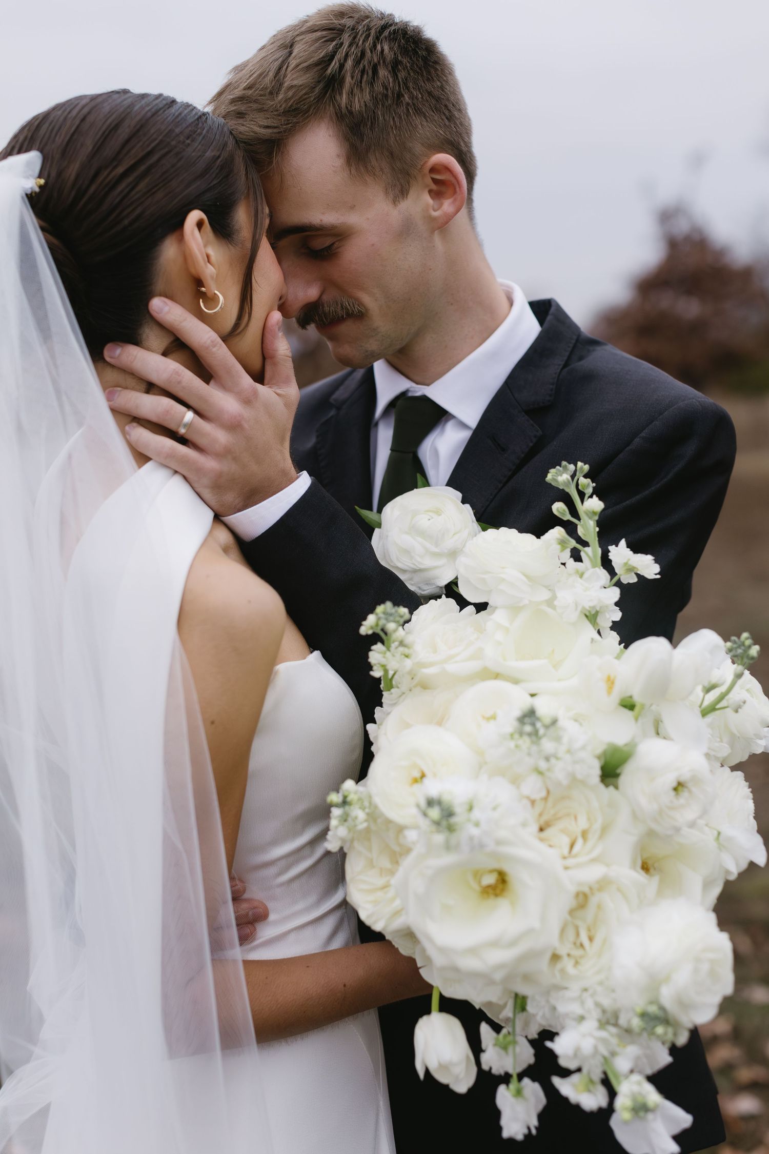 Intimate wedding photos with white floral bouquet and romantic poses against natural backdrop.