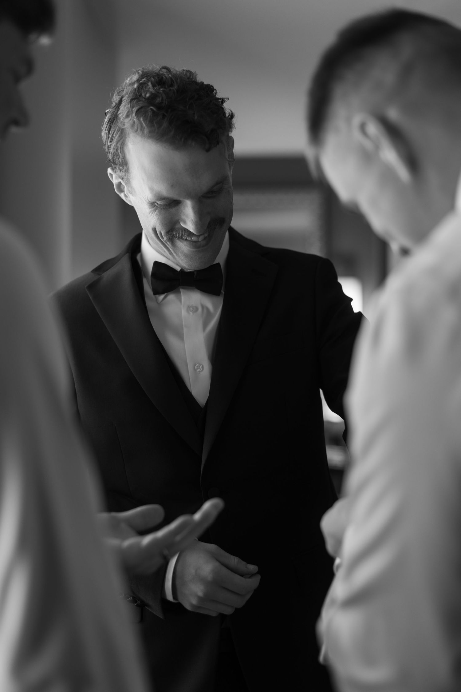 Men in formal attire preparing for an event in dramatic lighting.