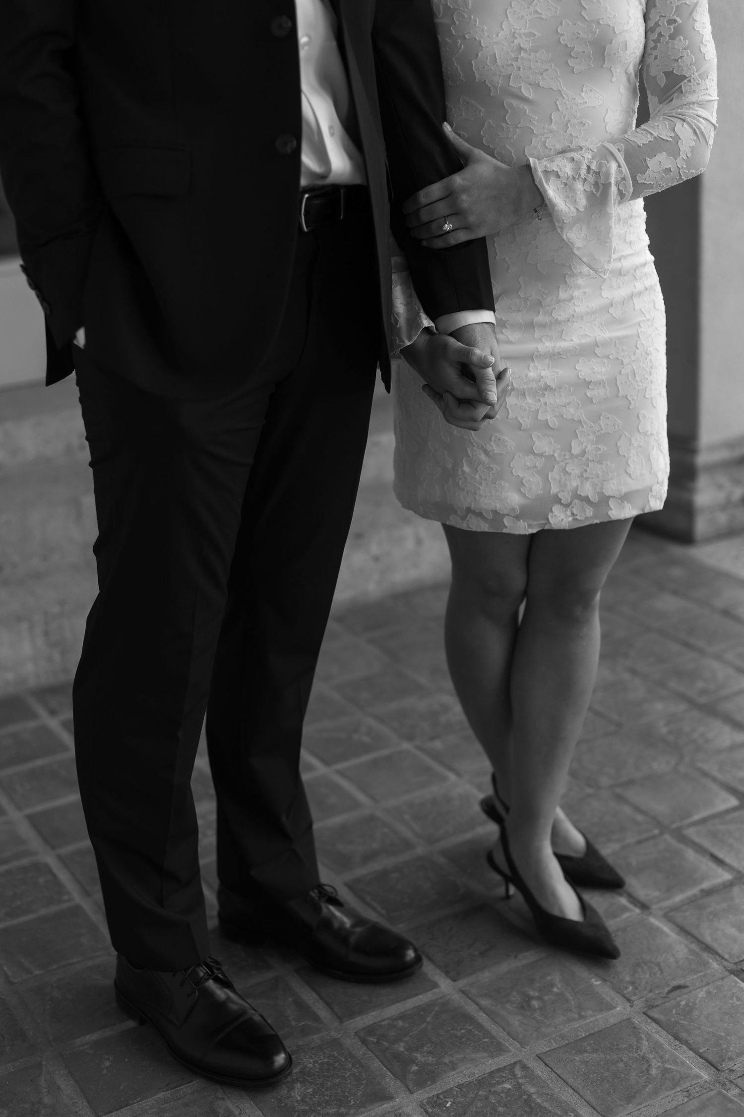 A close-up shot of formal shoes and dress attire on a tiled floor.