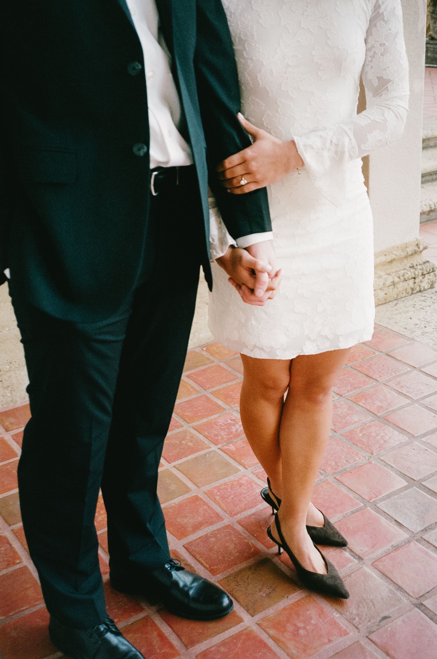 Close-up of formal attire showing emerald suit jacket and white lace dress.