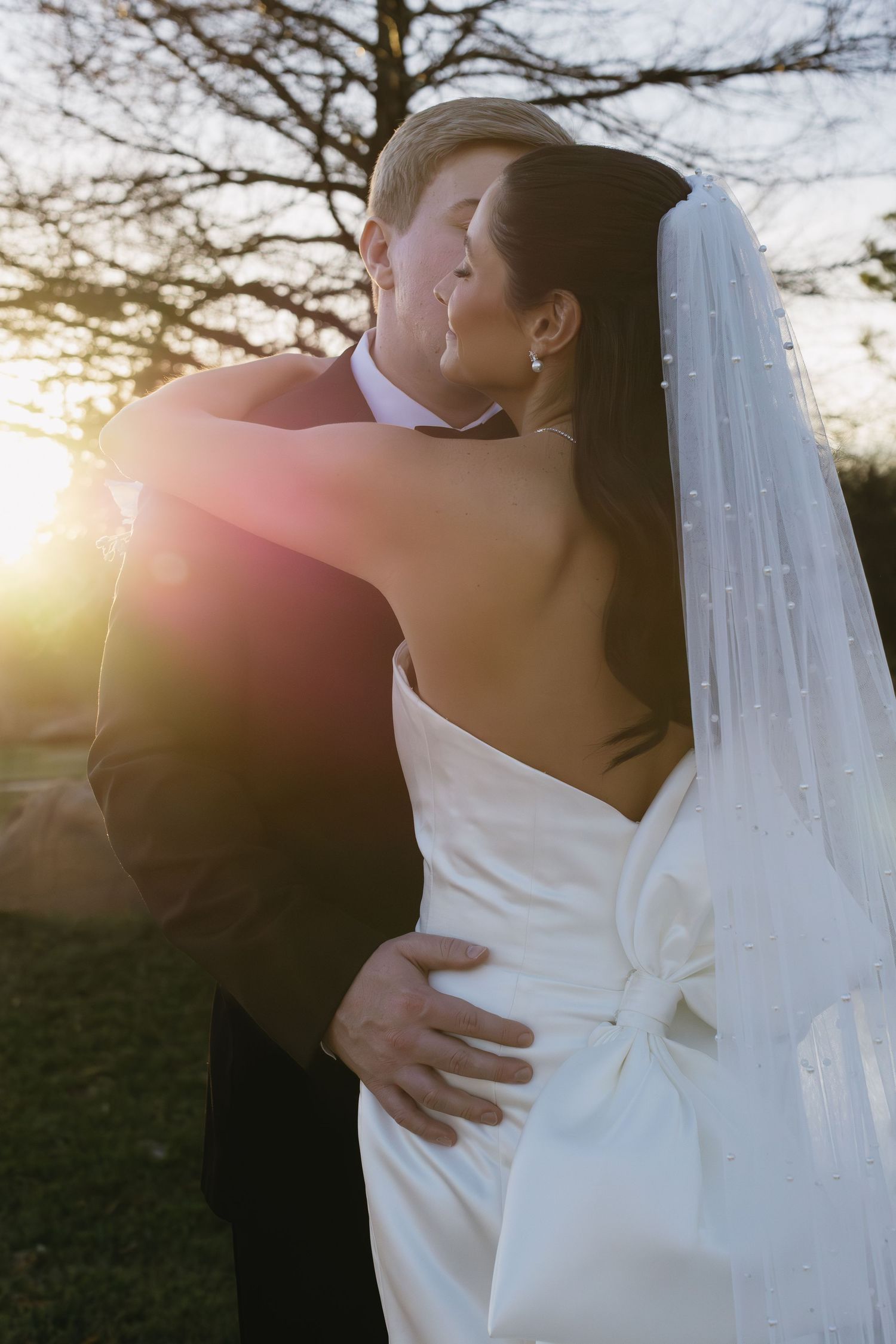 Intimate moment between newlyweds during sunset outdoor portrait session.