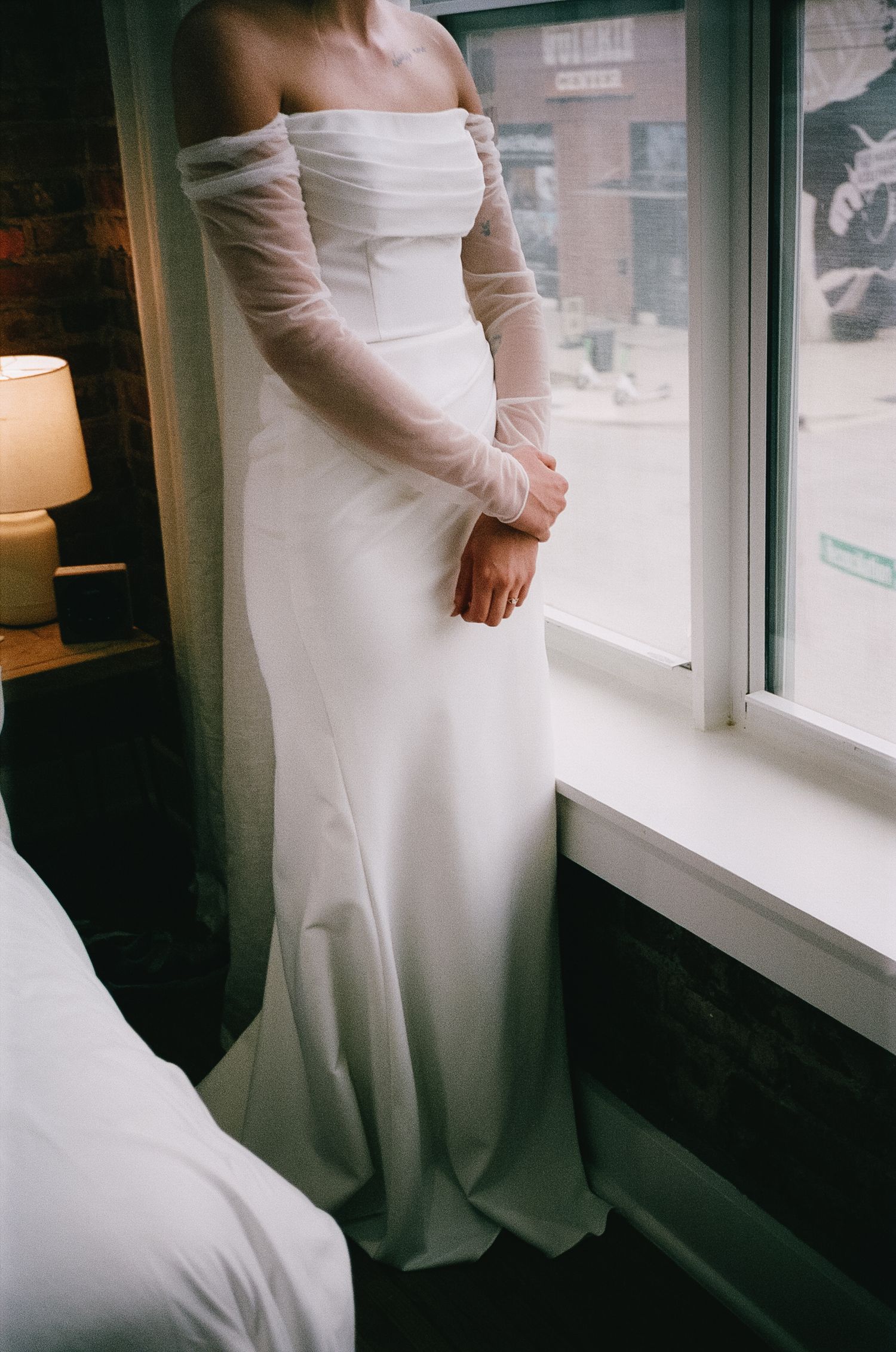 Elegant white wedding dress details photographed near a window in natural light.