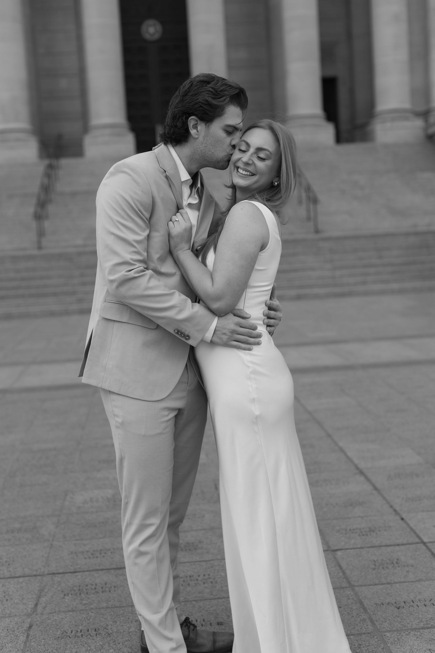 Black and white portrait of a couple sharing tender moments in formal attire.